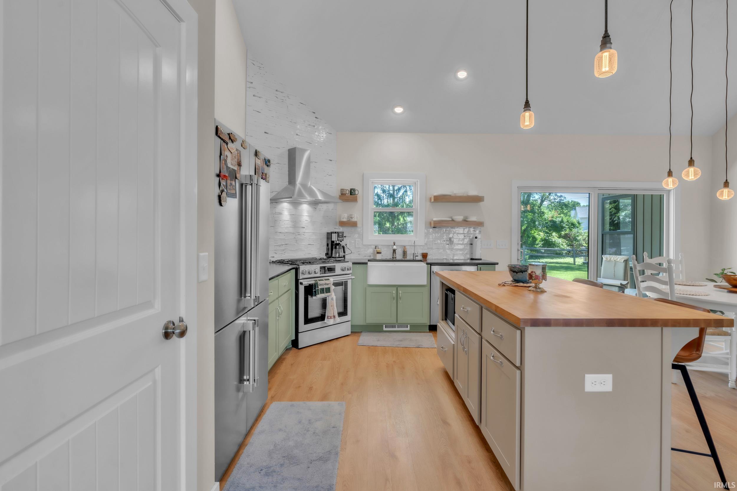 Spacious kitchen featuring an island with wood-finish countertop, stainless steel appliances, and wood-finish flooring