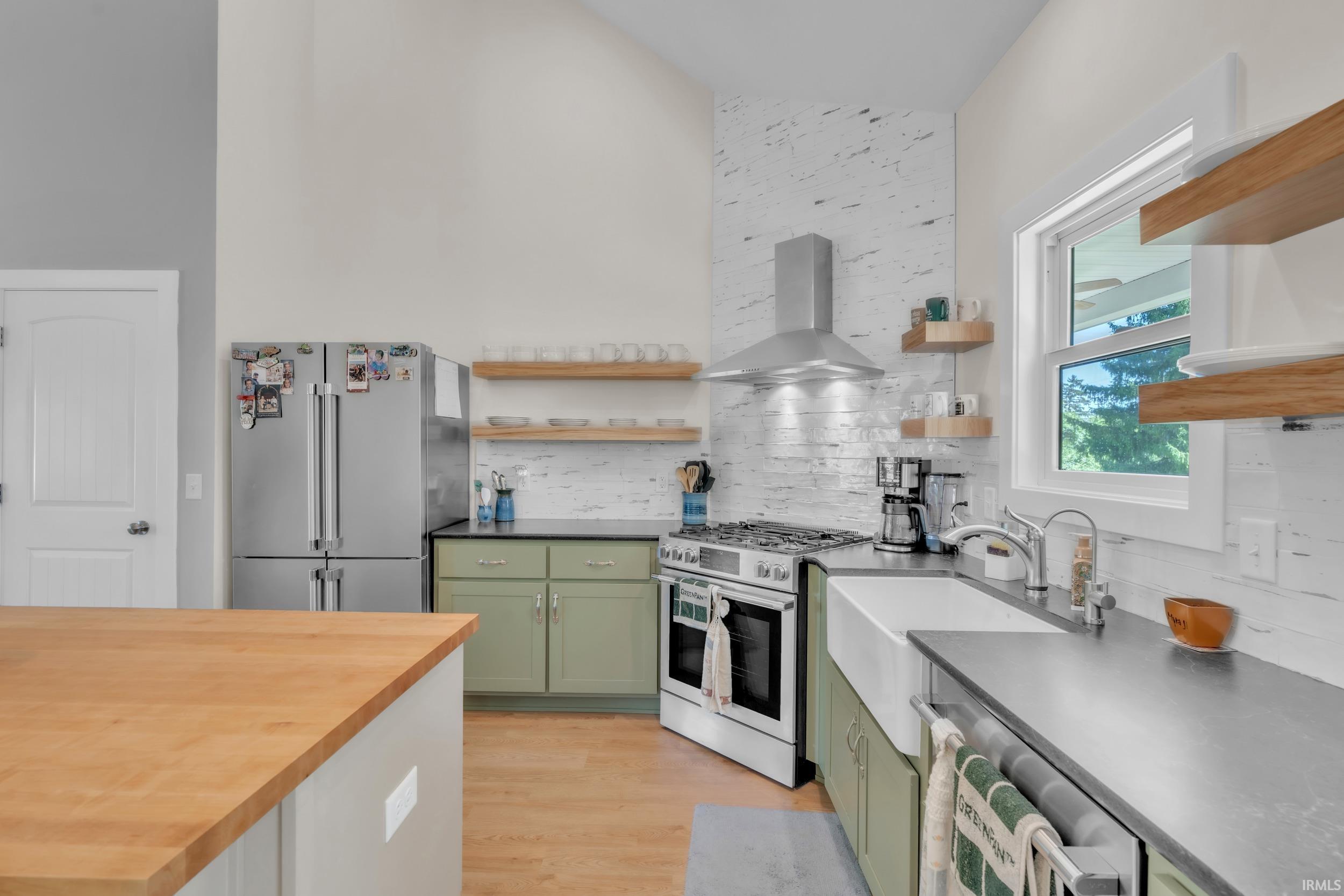 Kitchen featuring light wood-finish flooring, sage green lower cabinetry, and dark countertops