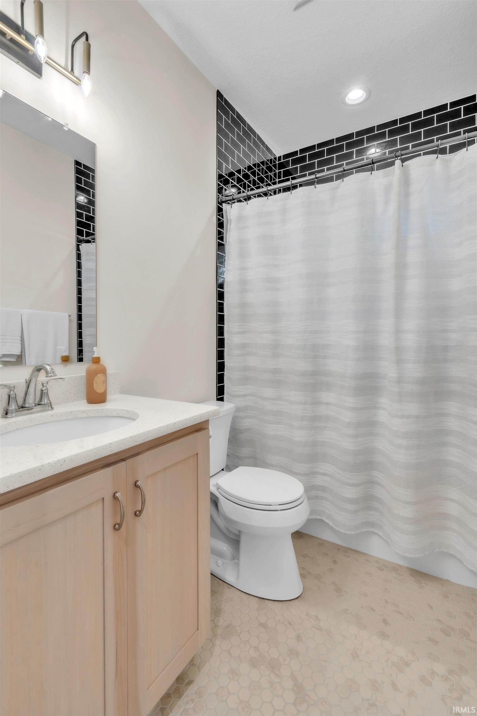 Bathroom vanity with light wood-finish cabinetry, white countertop, and integrated sink