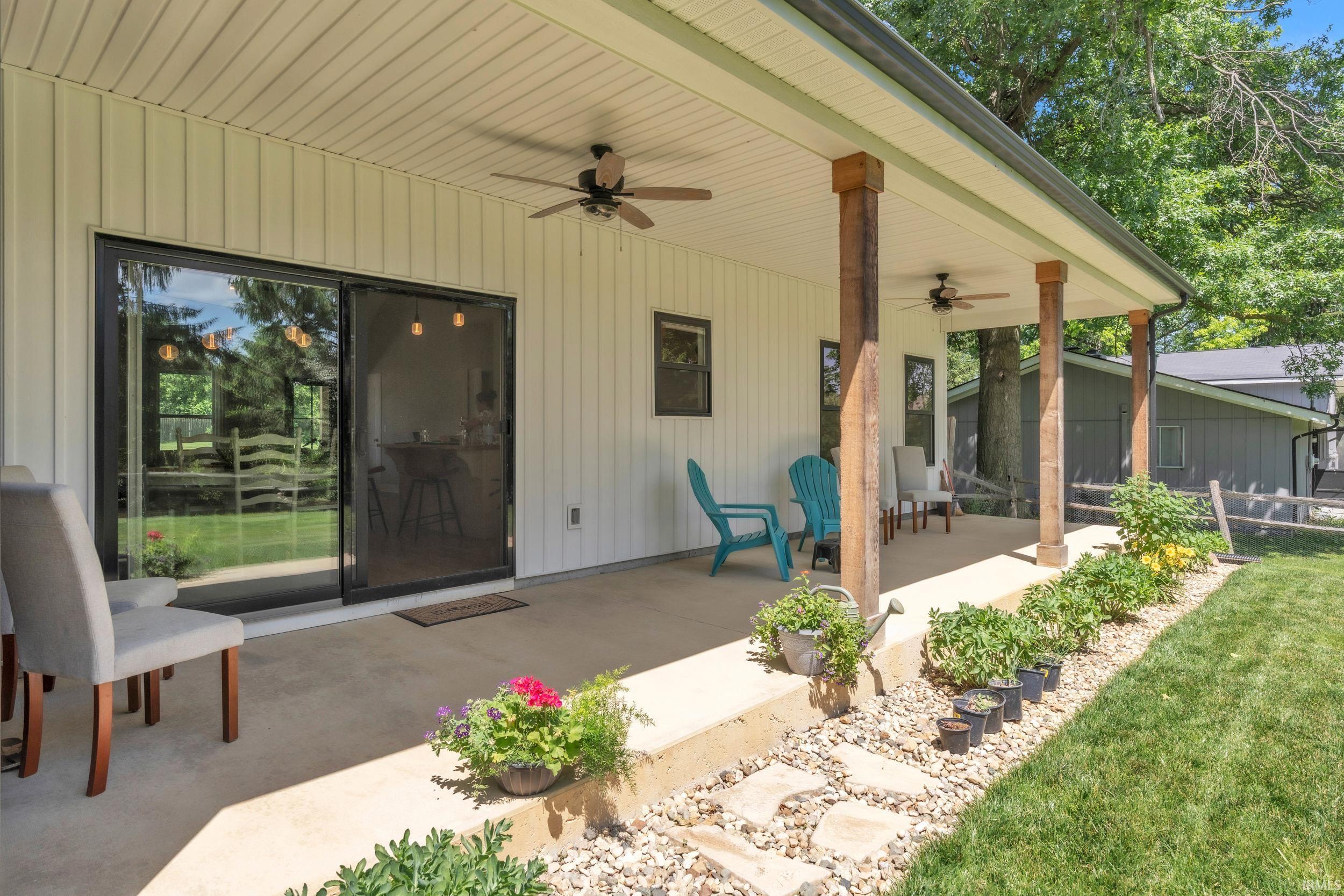 Spacious covered patio featuring durable concrete flooring, exposed wood support beams, and ceiling fans