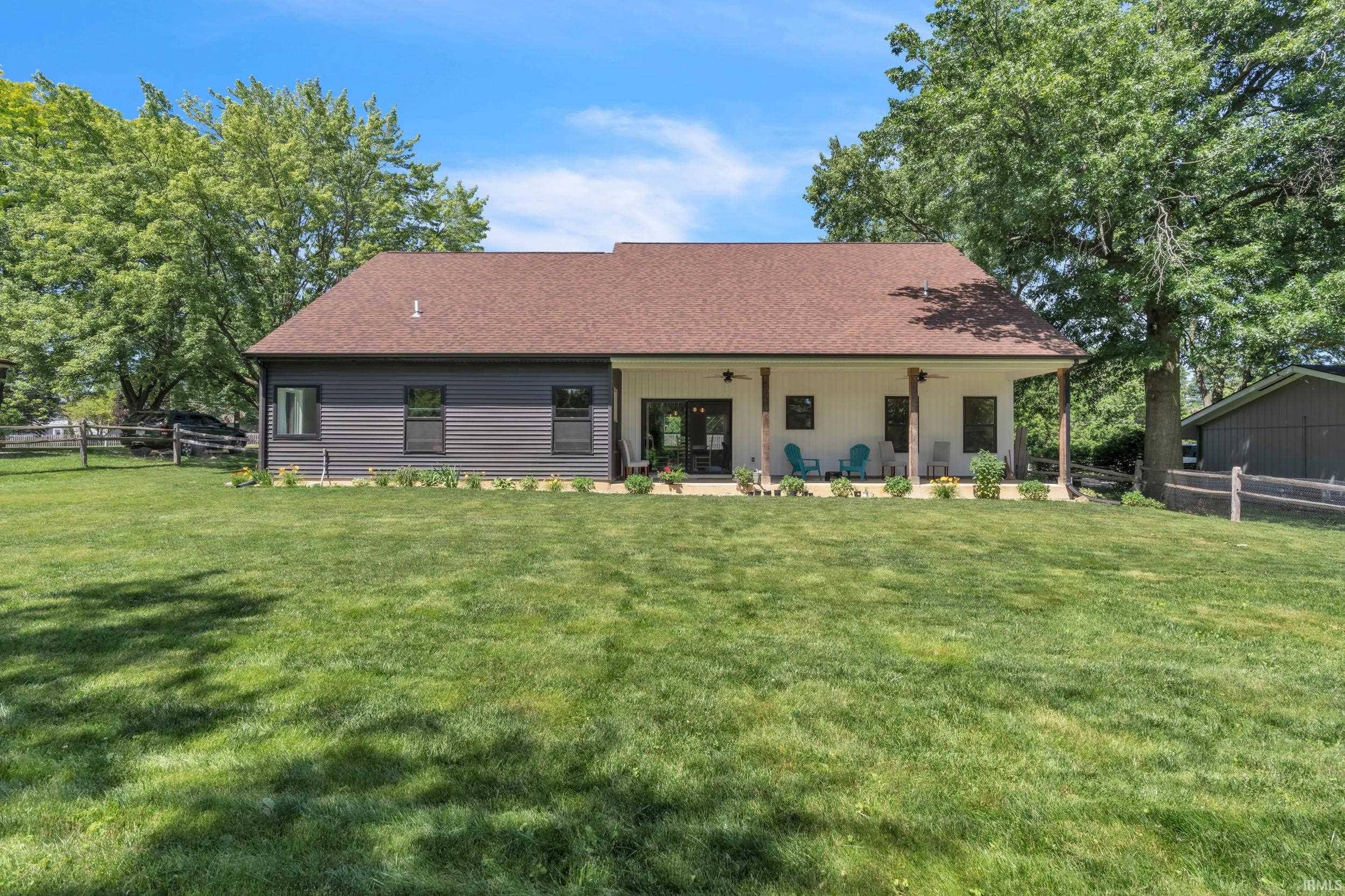 Expansive lawn featuring a contemporary home with a covered patio, multiple exterior doors, and dark-framed windows