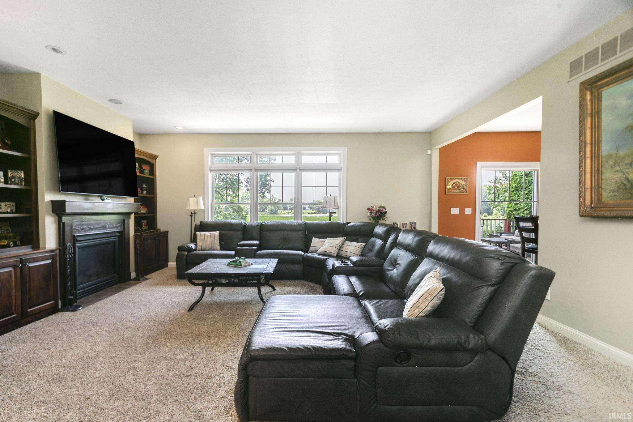 Living area featuring a fireplace with a dark wood mantel, built-in cabinetry, and neutral-toned carpeting