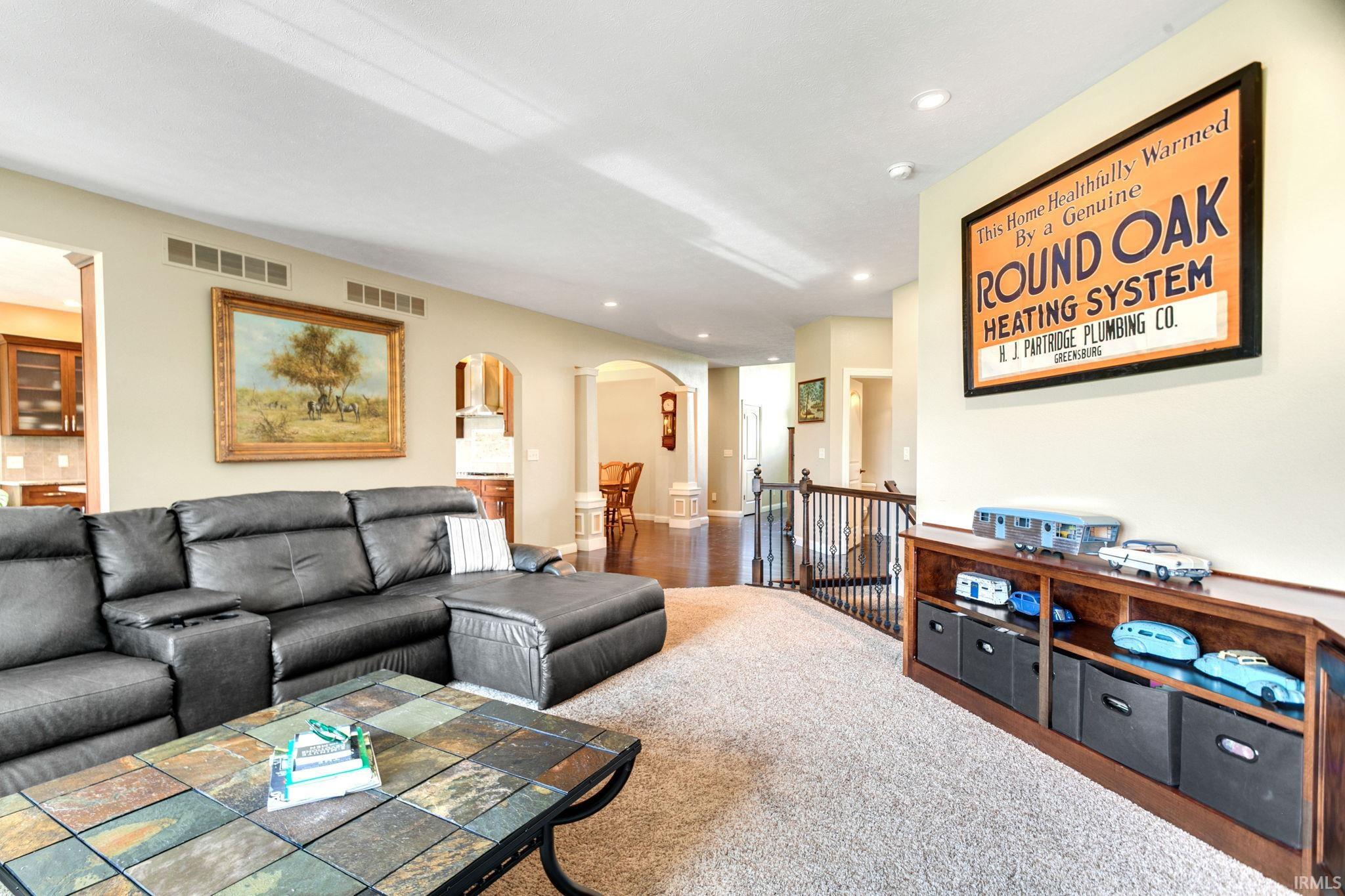 Carpeted common area featuring a built-in shelving unit, recessed lighting, and an arched entryway