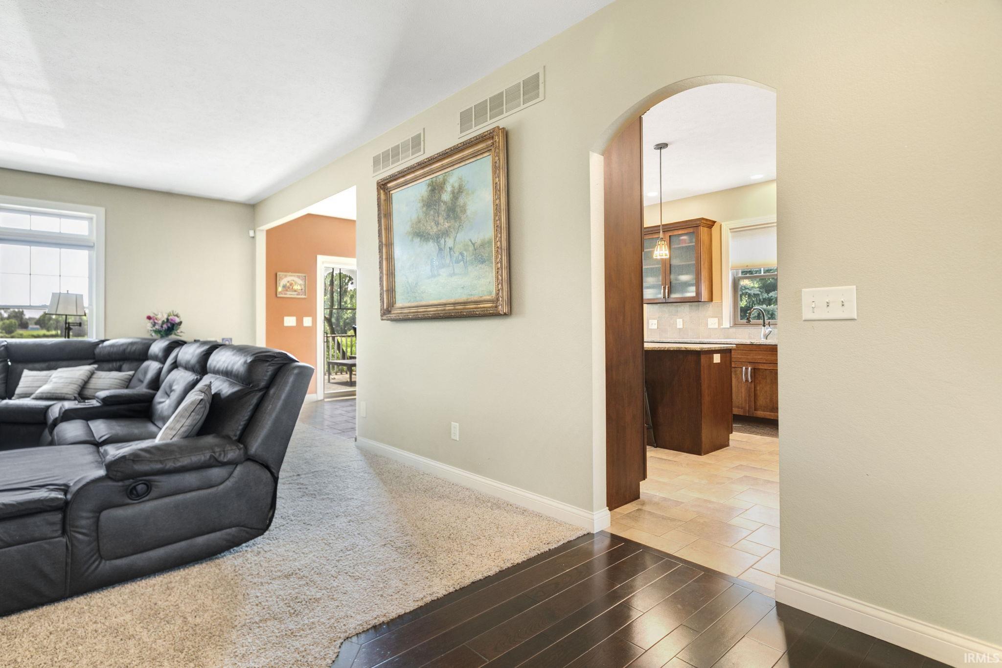 Archway entry to the kitchen featuring wood cabinetry and a tile backsplash