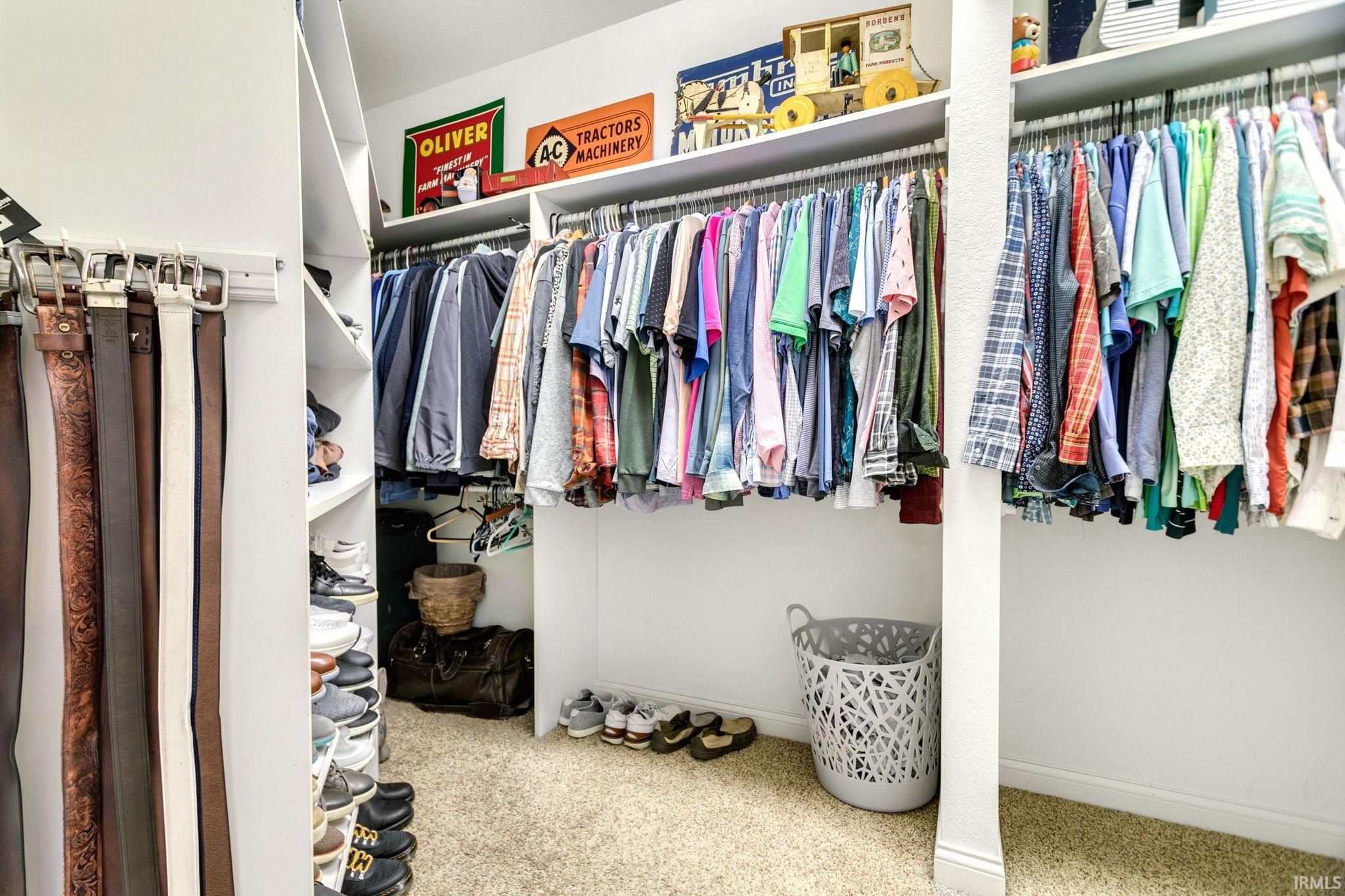 Custom closet organization system featuring white shelving, multiple hanging rods, and integrated belt racks