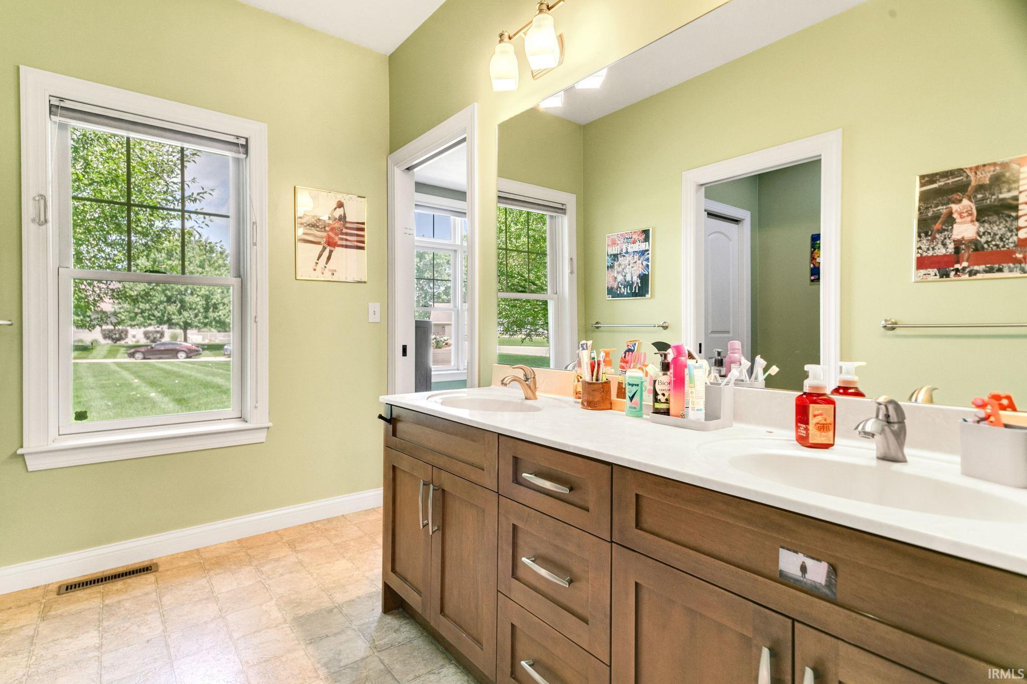 Double vanity with a white countertop and integrated sinks, wood-finish cabinetry, and chrome fixtures