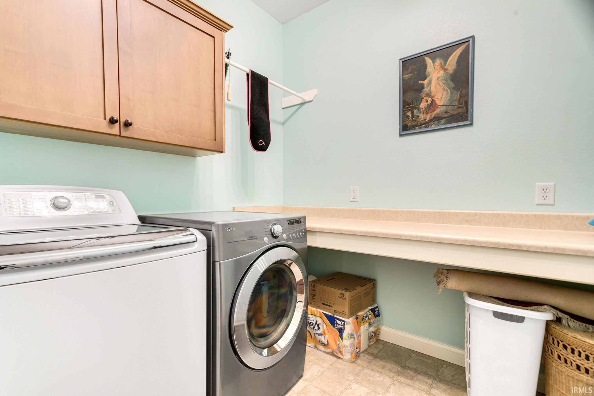 Laundry area featuring light wood cabinetry, a utility counter, and tile flooring