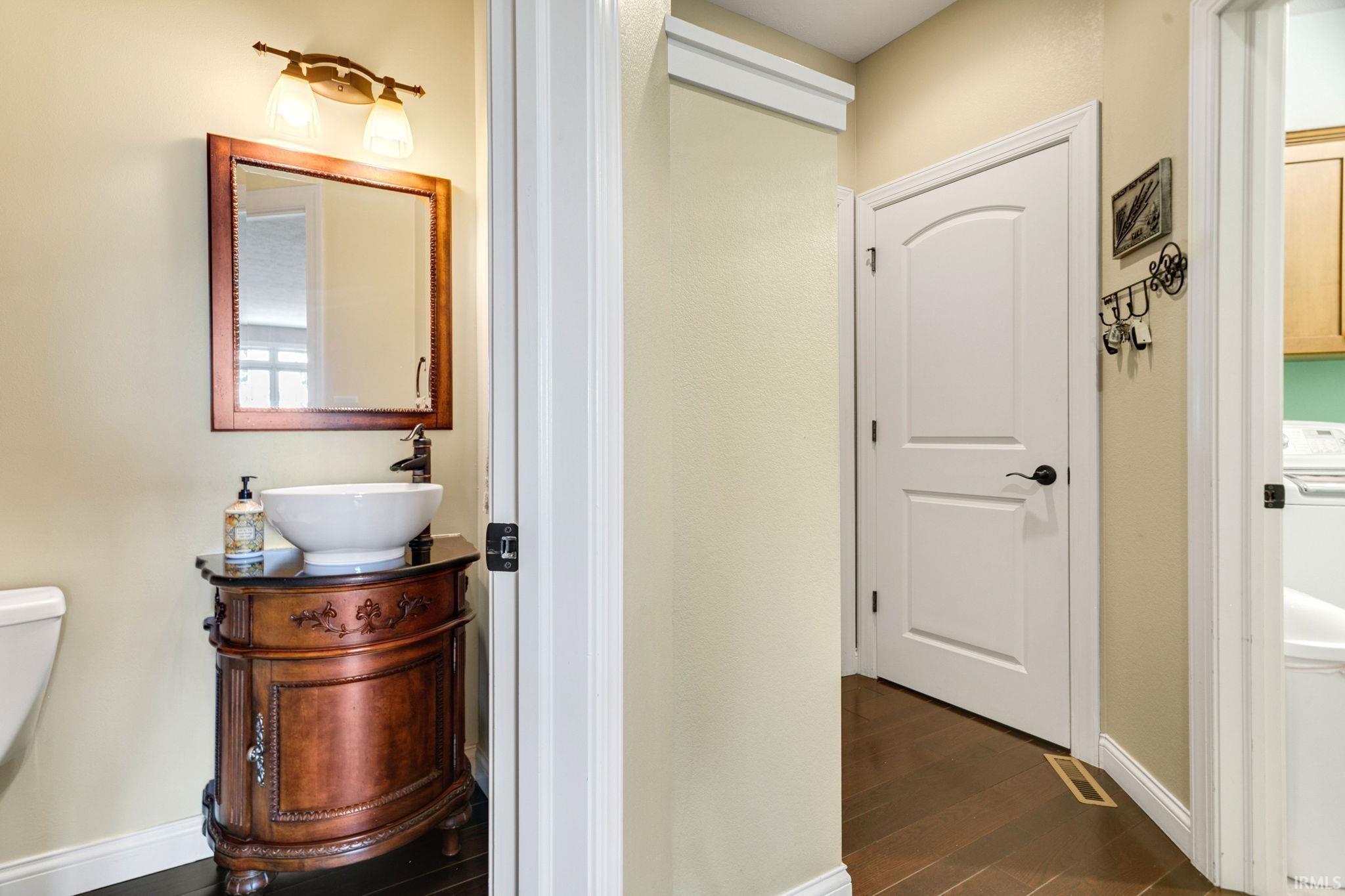 Bathroom vanity featuring a vessel sink, dark wood cabinetry, and a framed mirror