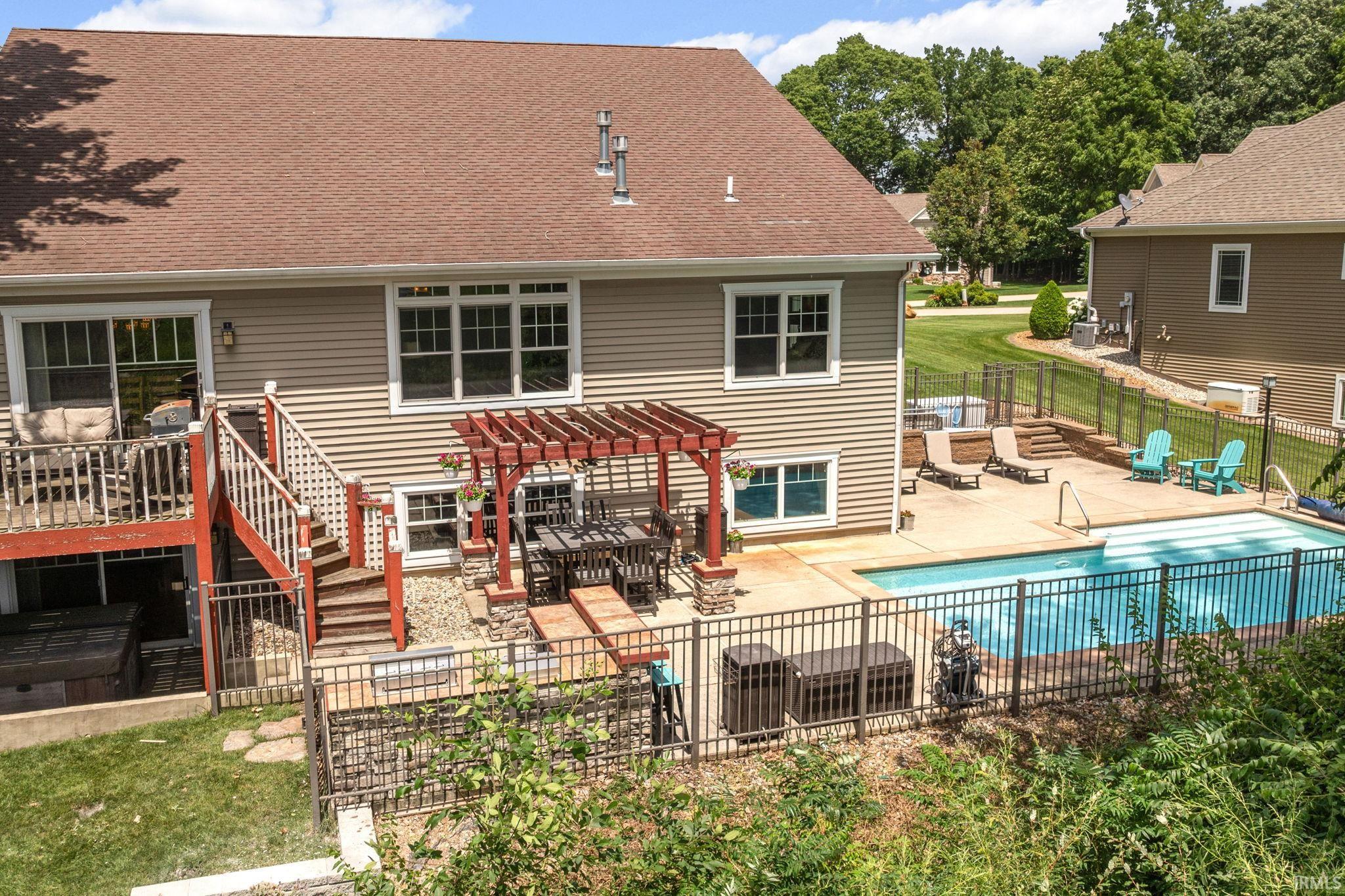 Rear exterior featuring an in-ground swimming pool, concrete patio, and a multi-level deck