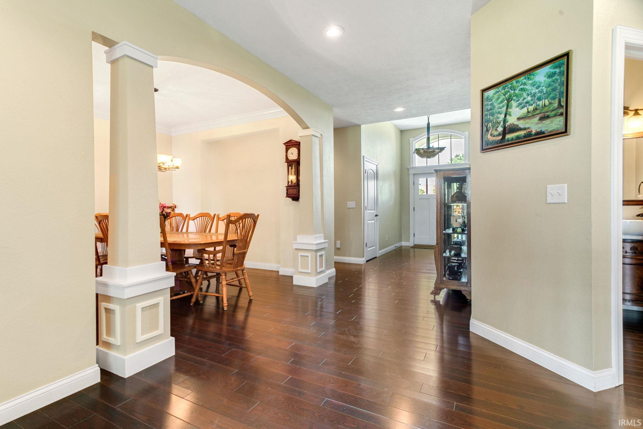 Expansive hallway featuring wood-finish flooring, decorative archways, recessed lighting, and a front entry with transom window