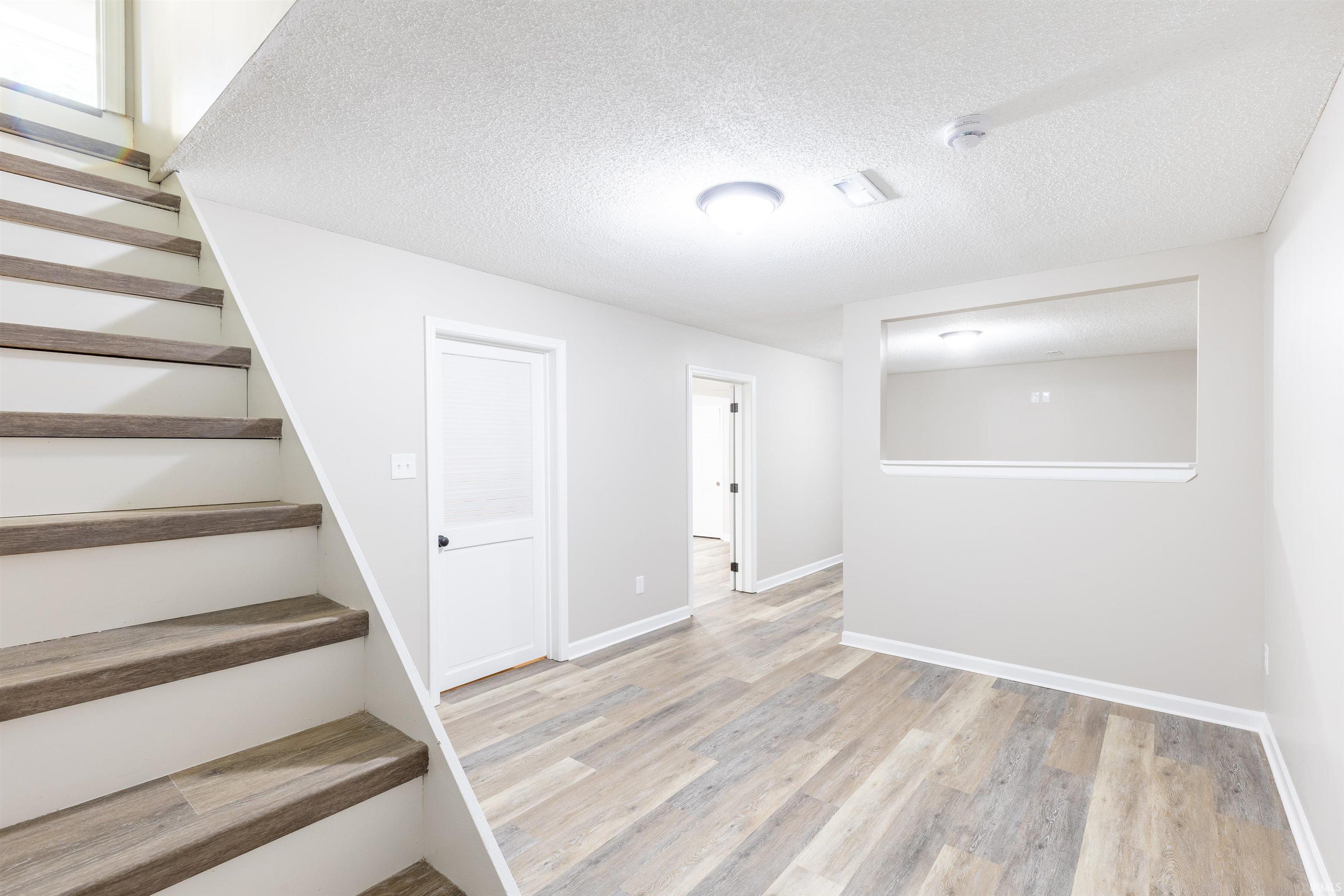 Finished room featuring wood-finish flooring, light neutral walls, and a recessed wall opening