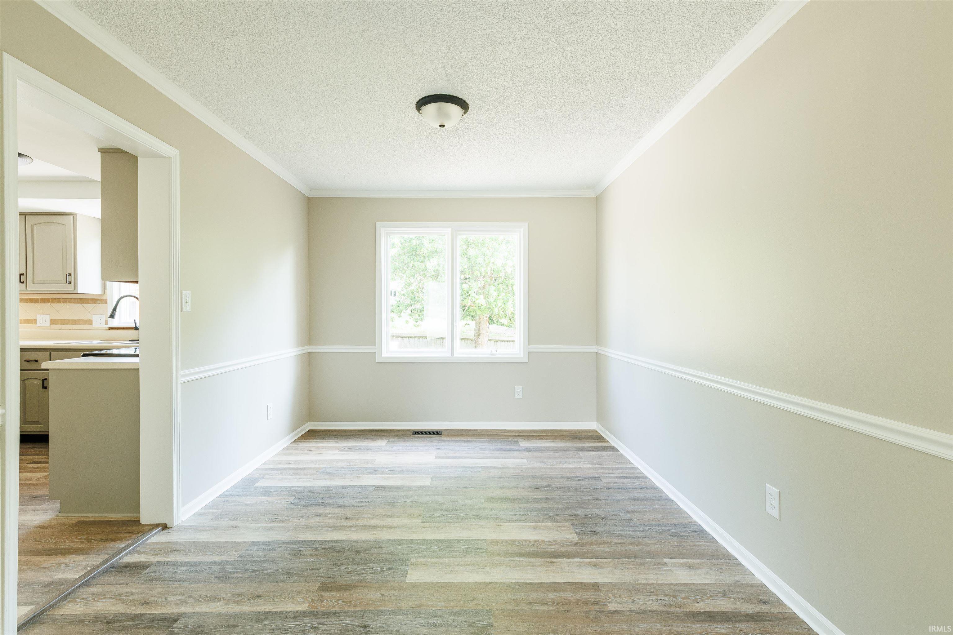 Spacious room featuring wood-finish flooring, neutral-toned walls, and white trim