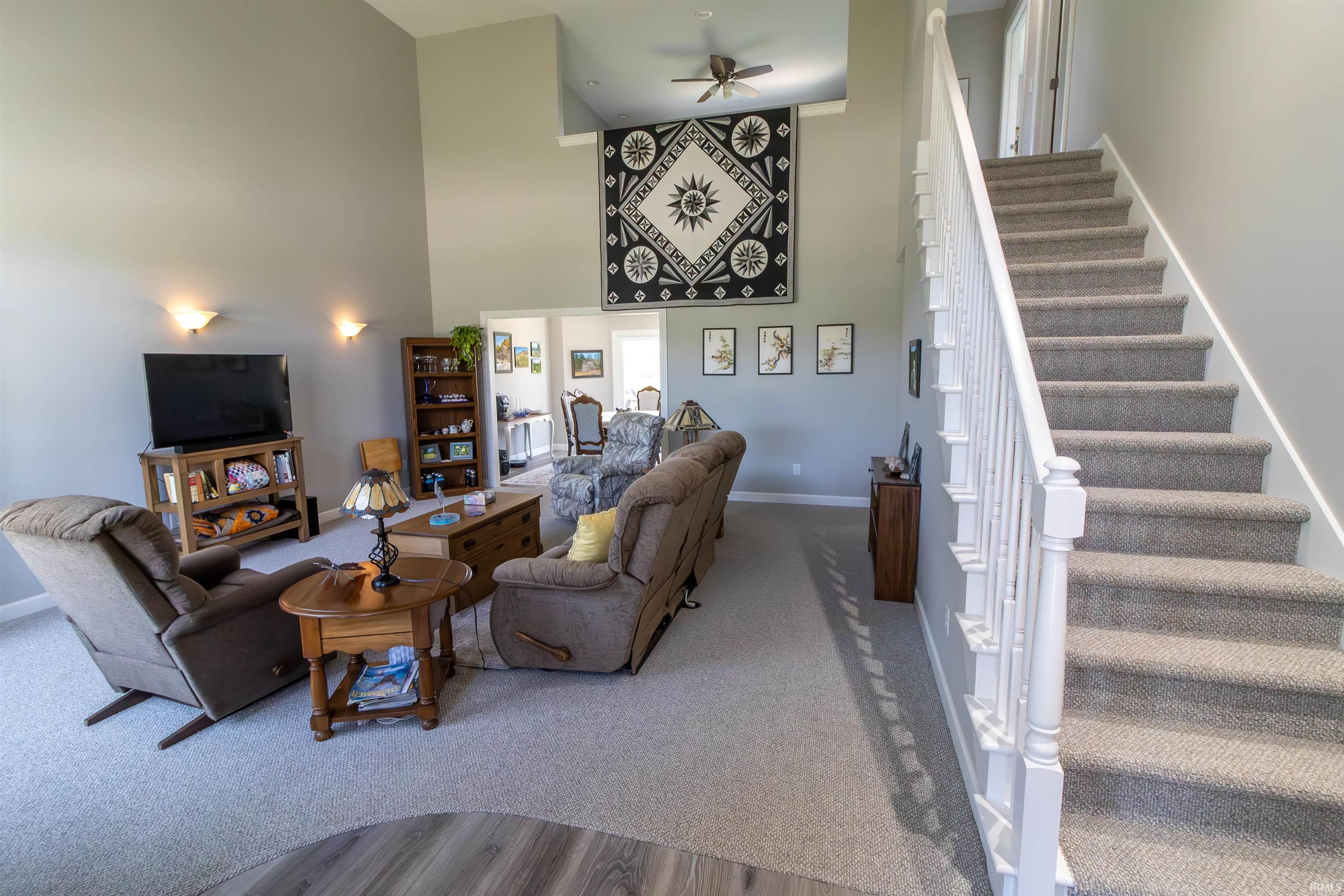 Two-story living area with vaulted ceilings, light gray wall paint, and carpet flooring