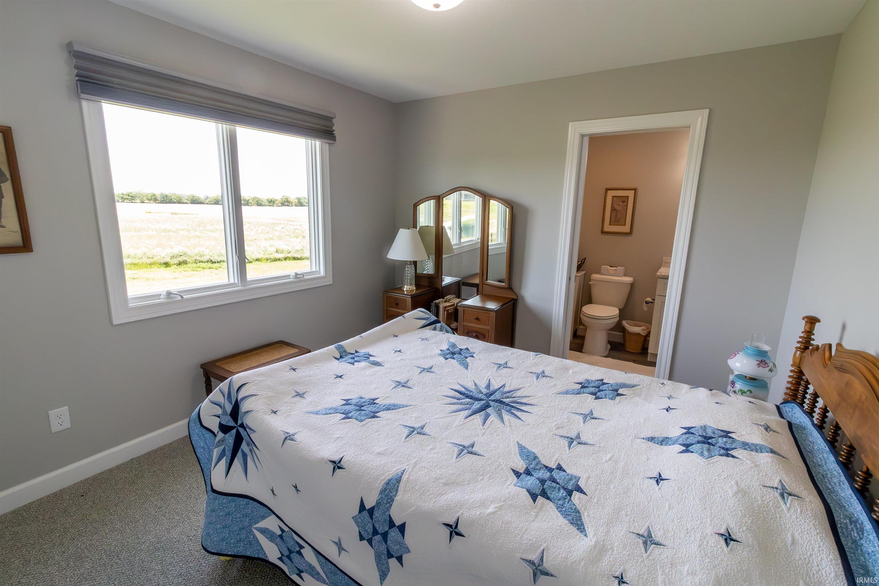Bedroom with light gray walls, white trim, and a window featuring a gray Roman shade