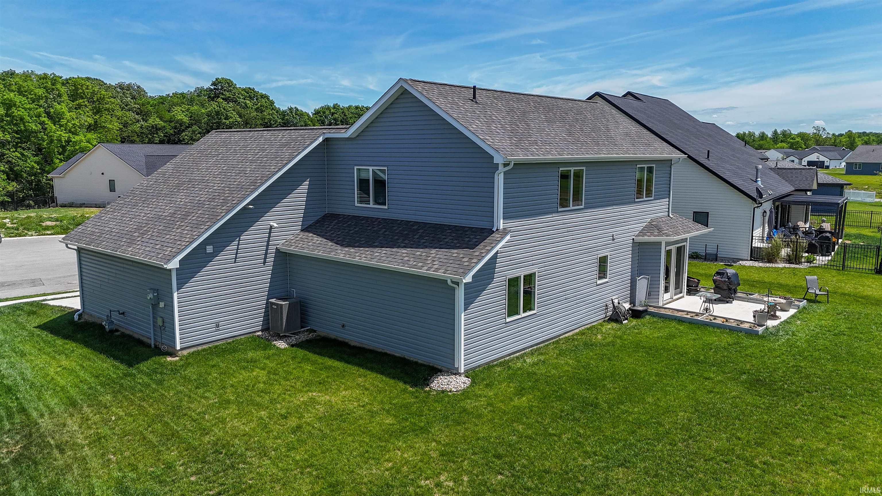 Rear exterior featuring light blue siding, a stone paver patio, double French doors, and a manicured lawn