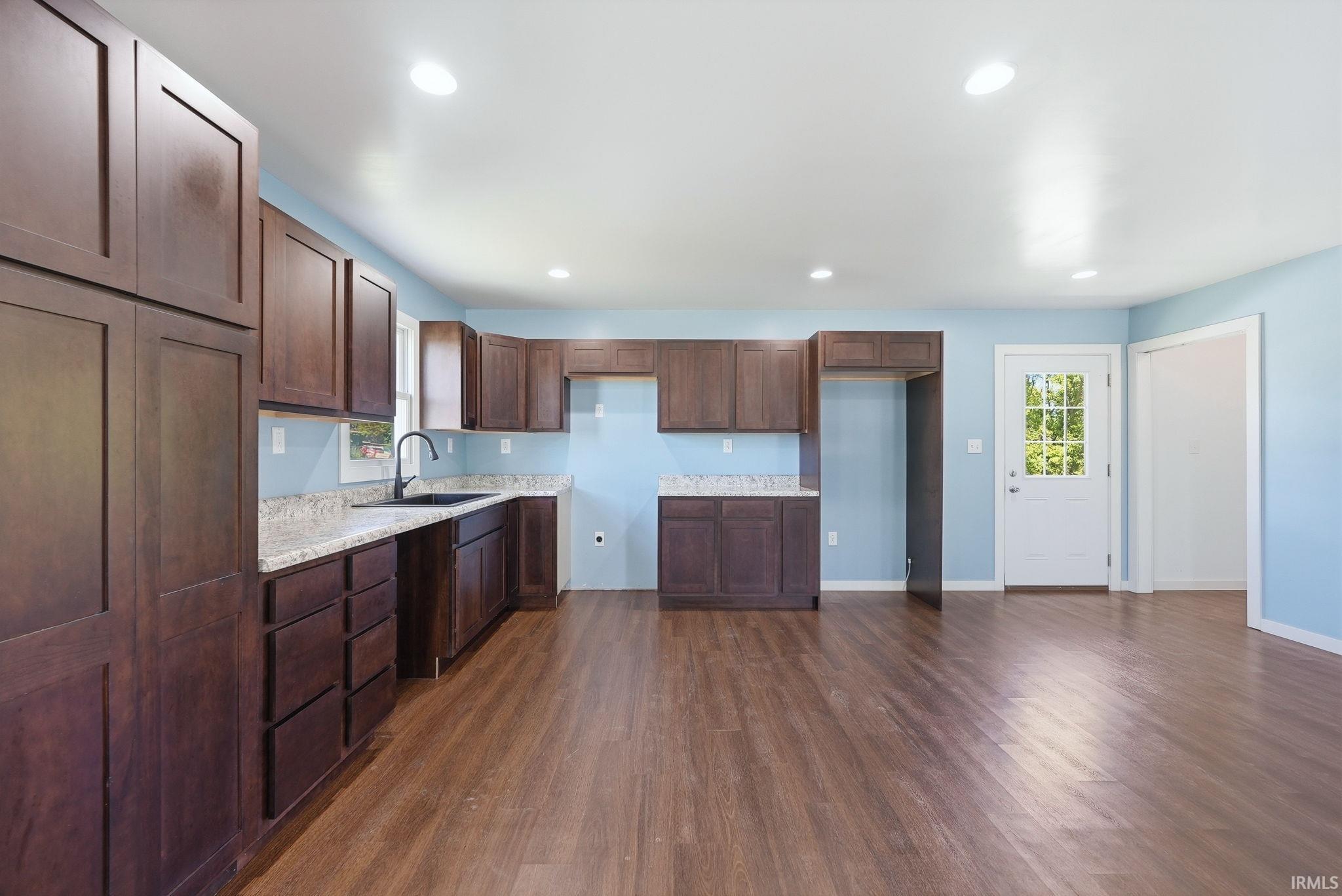 Kitchen featuring dark wood-finish cabinetry, light-colored countertops, and a black sink with a matte black faucet