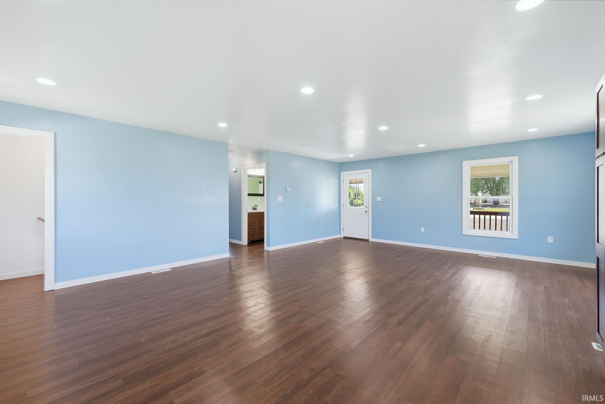 Spacious interior featuring wood-finish flooring, light blue walls, recessed lighting, and white trim