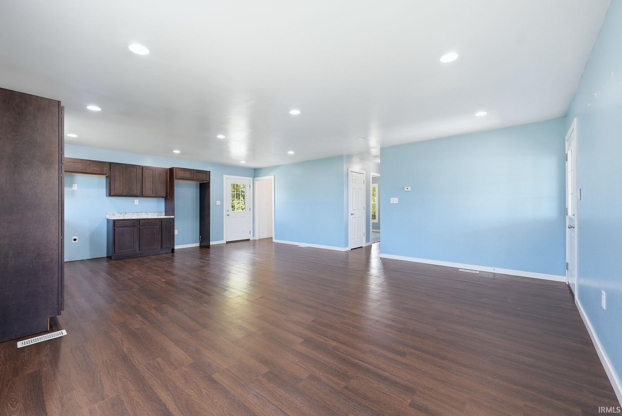 Spacious interior featuring wood-finish flooring, recessed lighting, and light blue wall tones