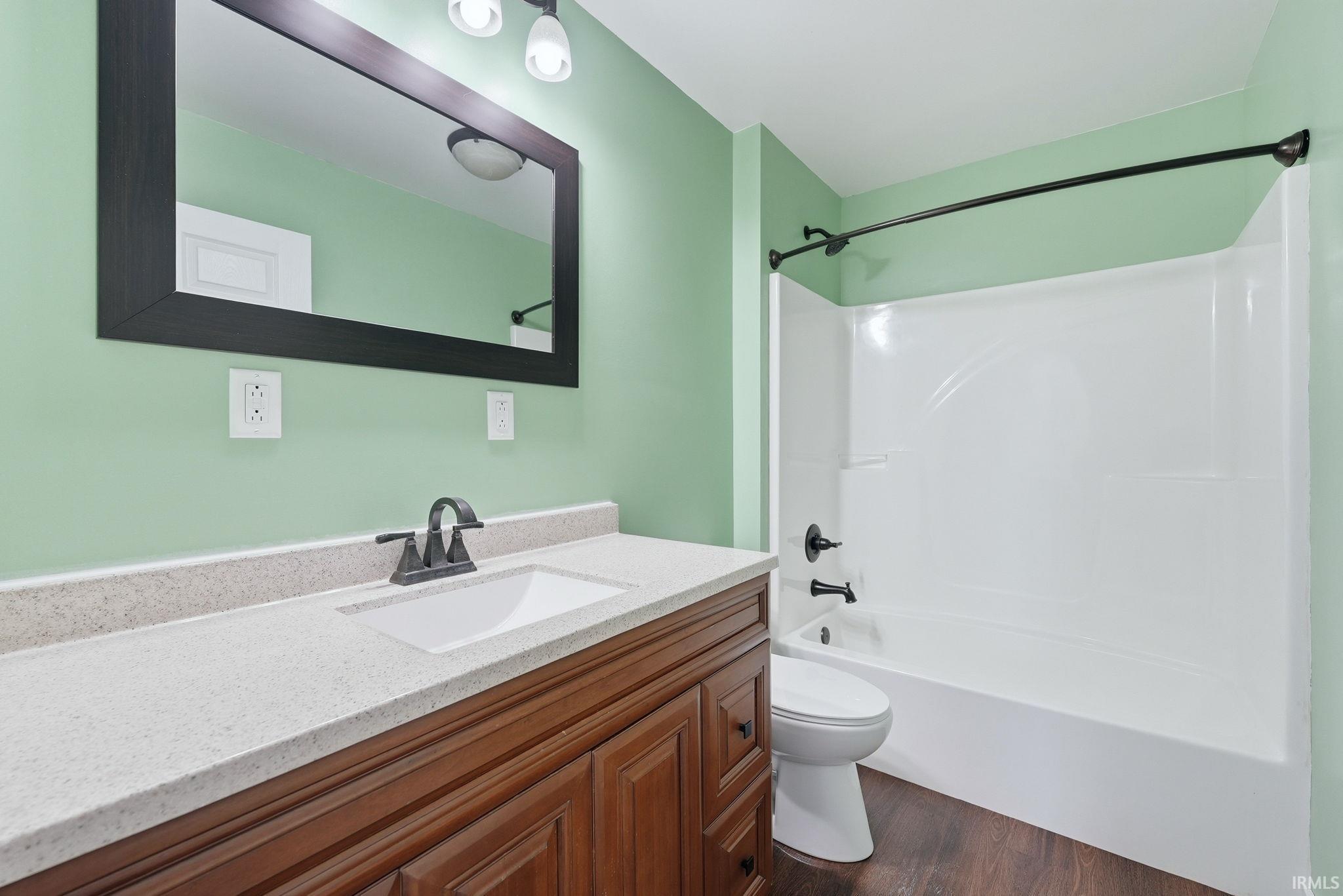 Bathroom featuring a wood-finish vanity with a light-toned countertop, an undermount sink, and dark-toned fixtures