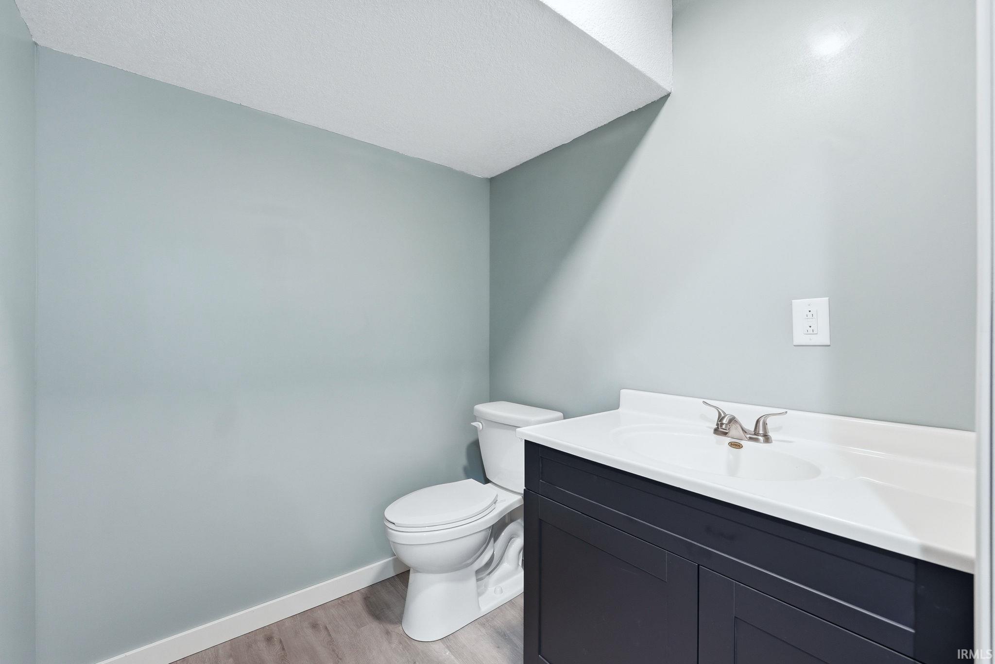 Bathroom featuring a vanity with a white countertop and integrated sink, brushed nickel faucet, dark blue cabinetry, and light wood-finish flooring