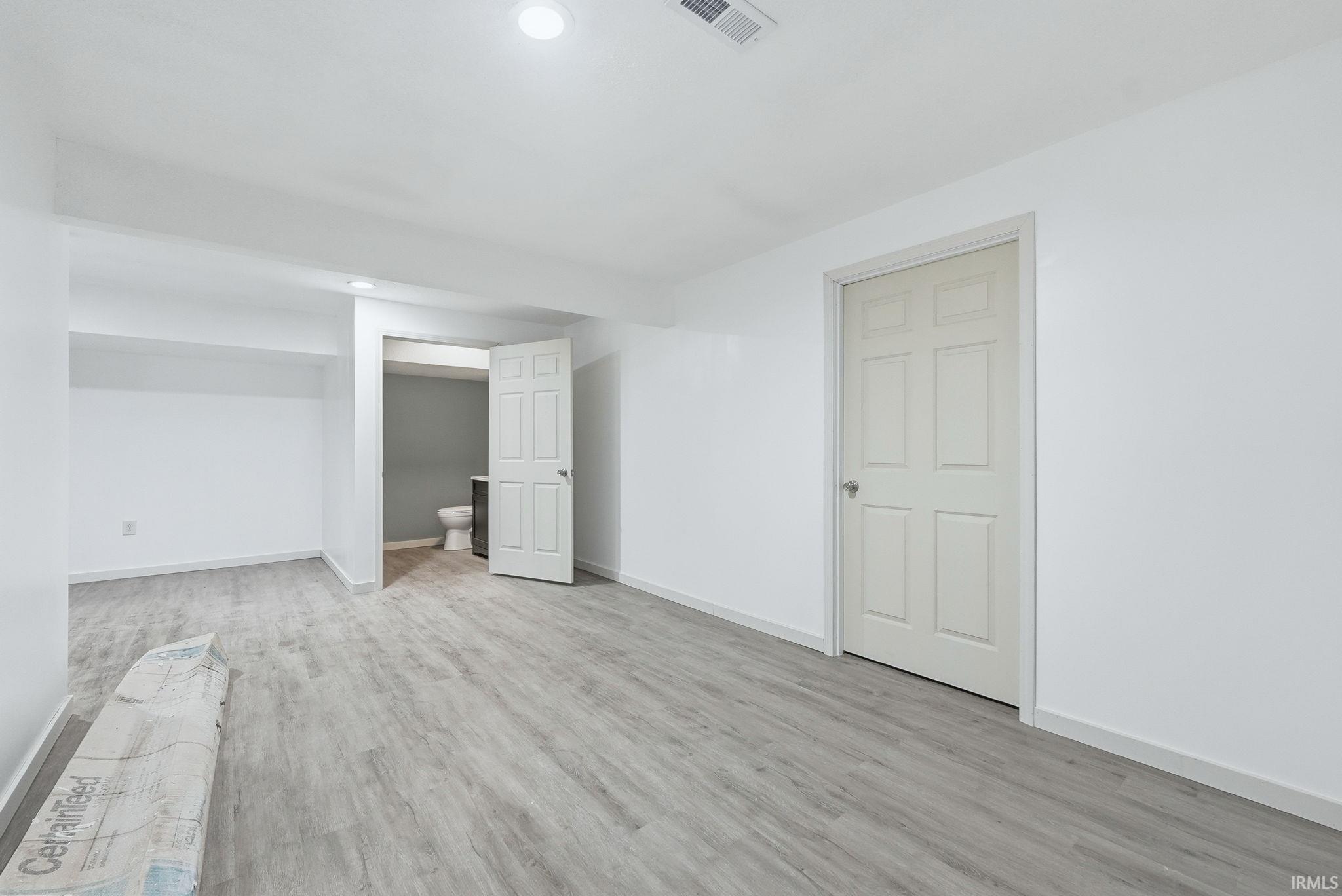 Spacious room featuring light wood-finish flooring and recessed lighting