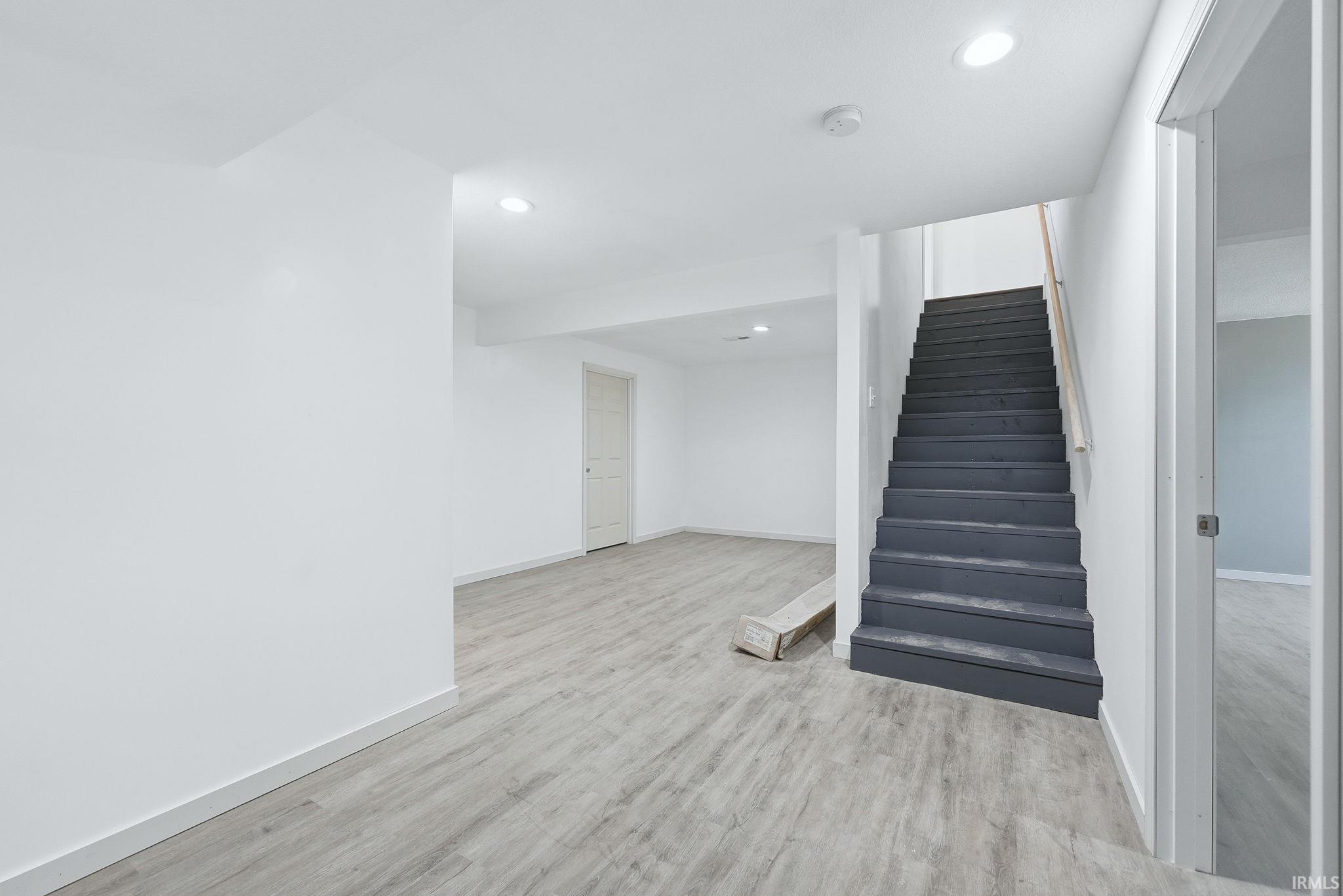 Open finished space featuring light wood-finish flooring, recessed lighting, and a neutral color palette