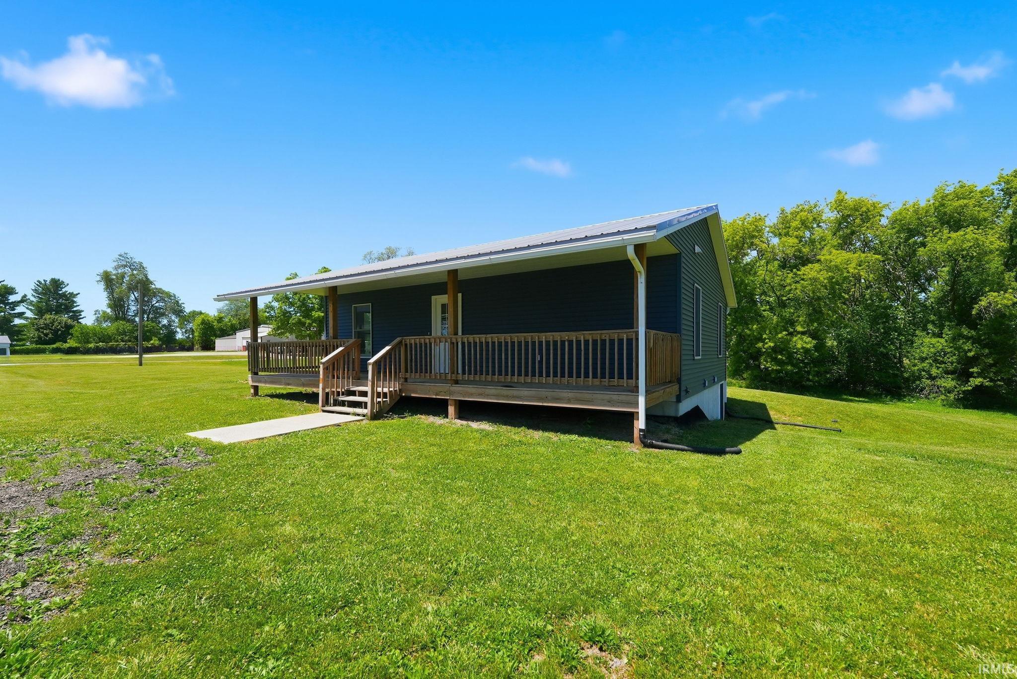 Exterior featuring dark siding, a covered porch with wood railings and posts, and a durable metal roof