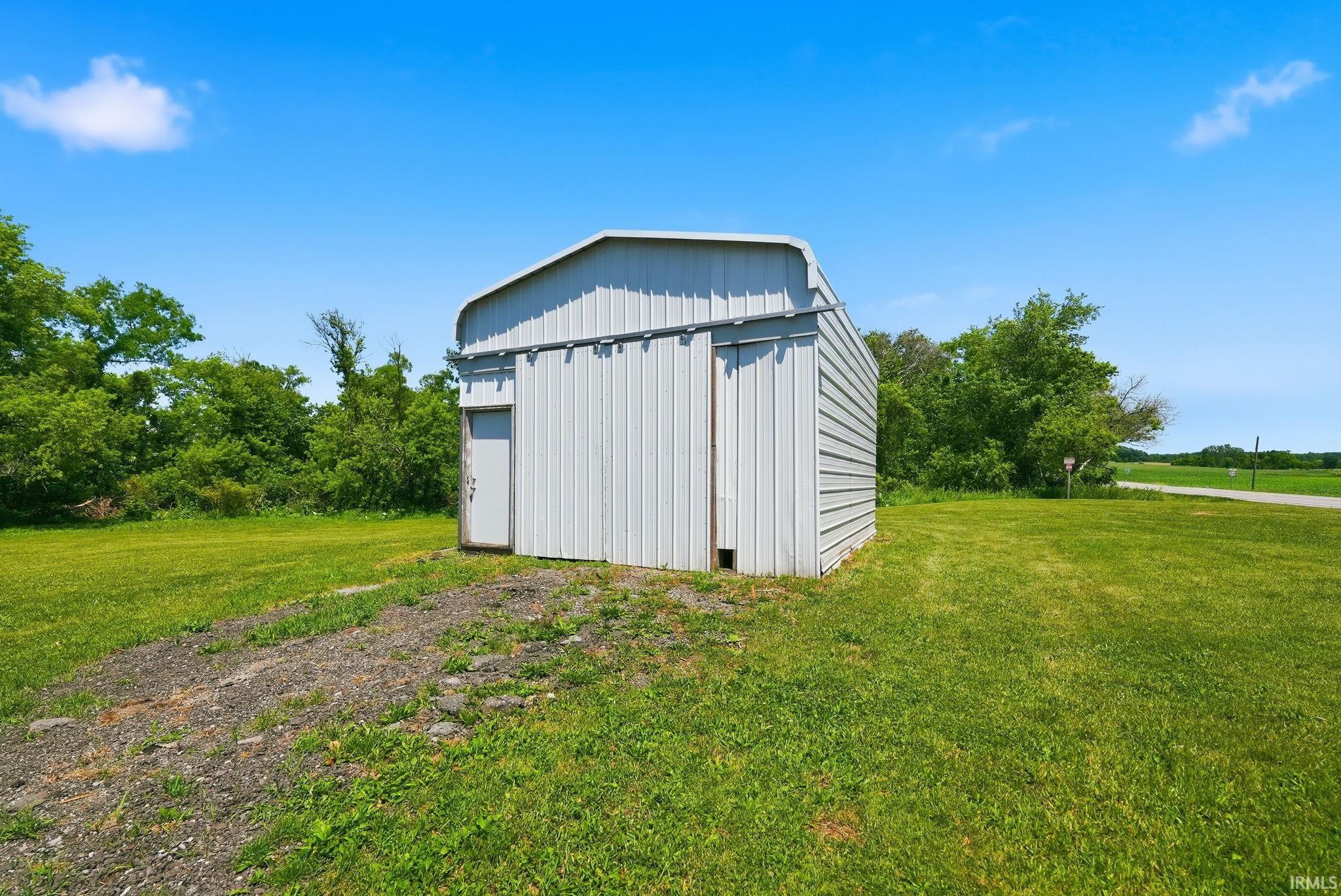 Freestanding metal utility building featuring a corrugated exterior and a side entry door