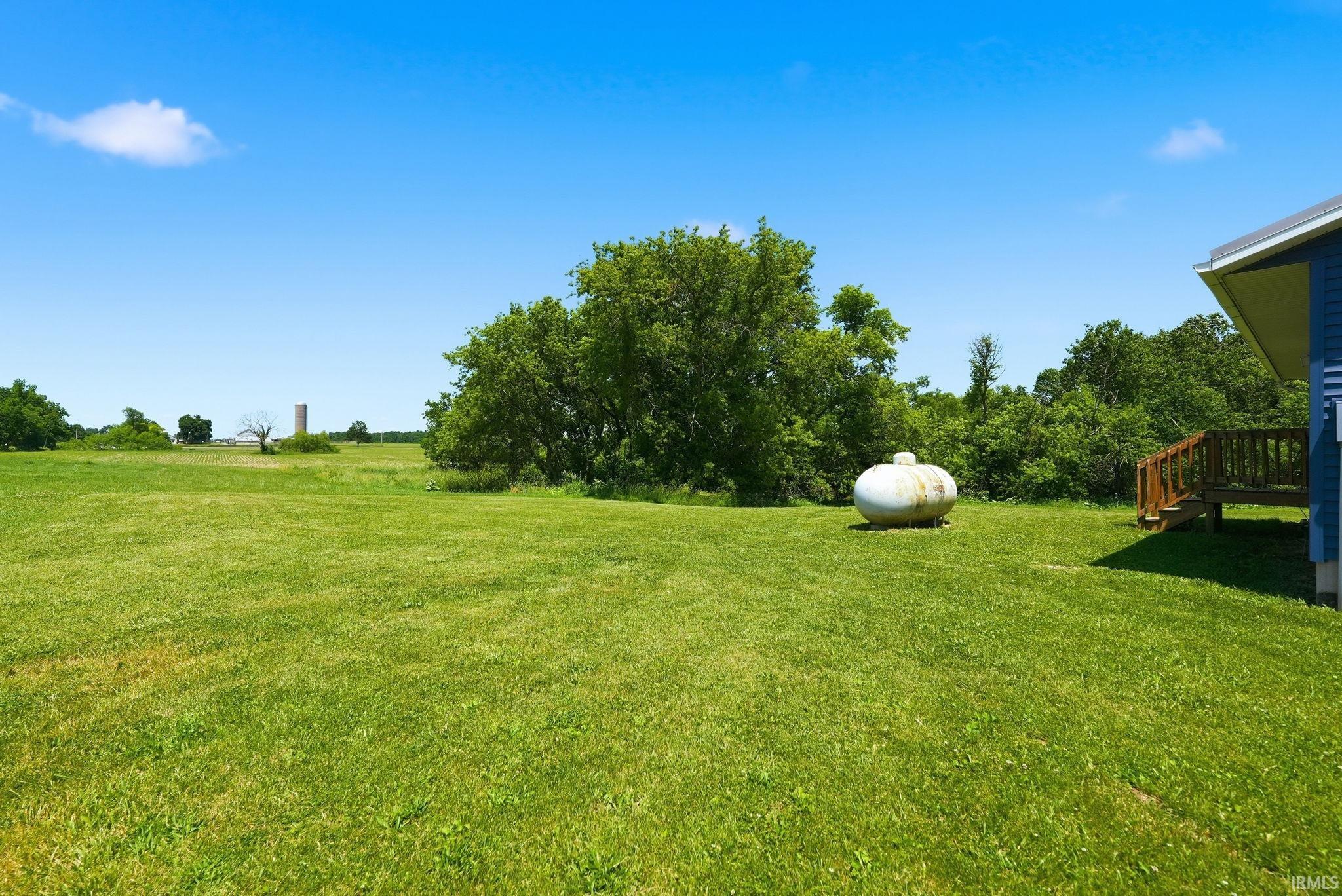 Expansive green lawn with mature trees bordering the property