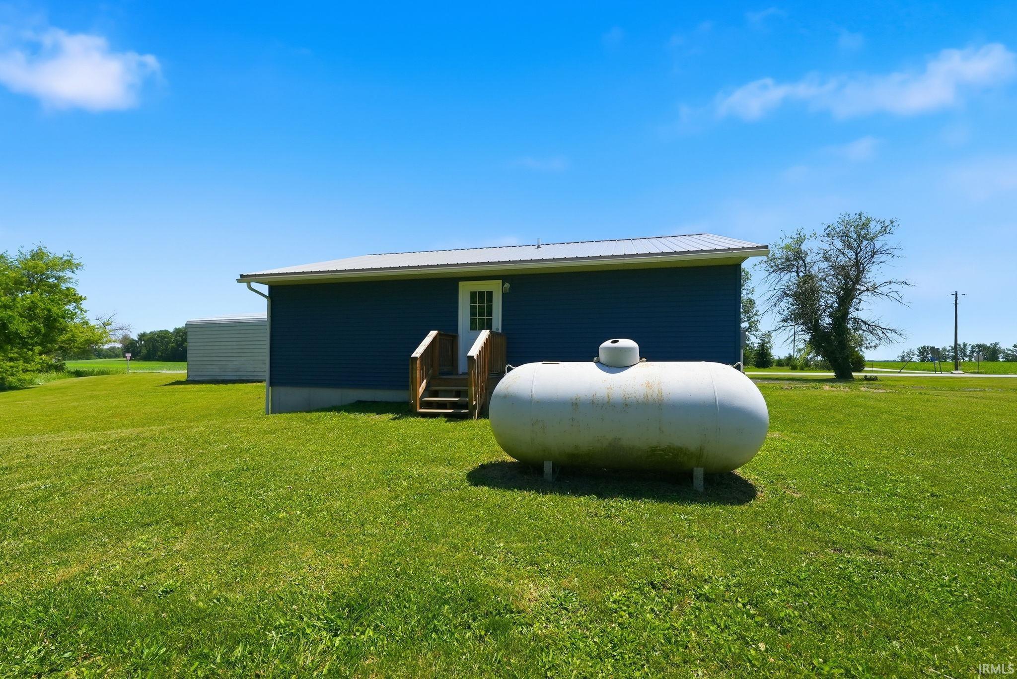 Rear exterior featuring blue siding, white trim, and a metal roof