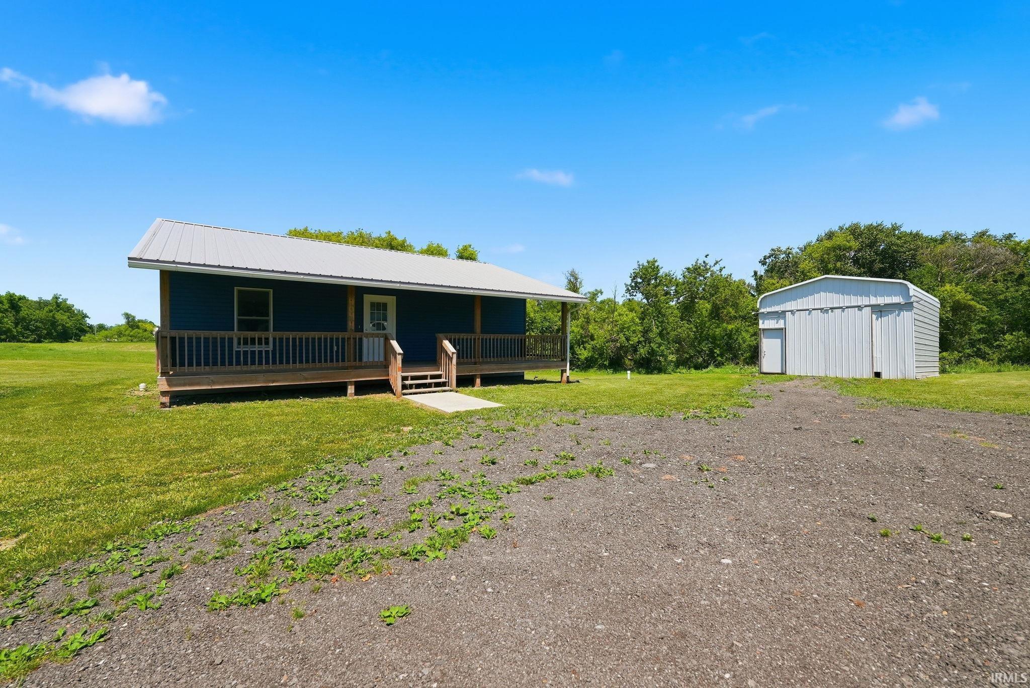 Blue exterior structure with a metal roof, front porch, and wooden railing