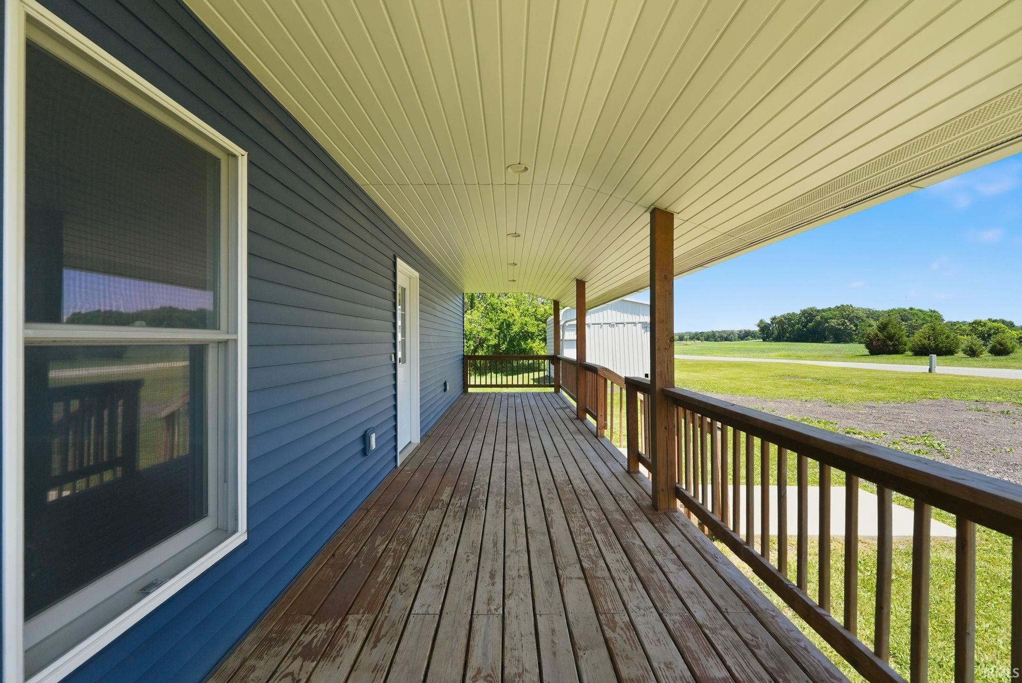 Expansive wooden porch extending the length of the residence, featuring horizontal blue siding and white trim