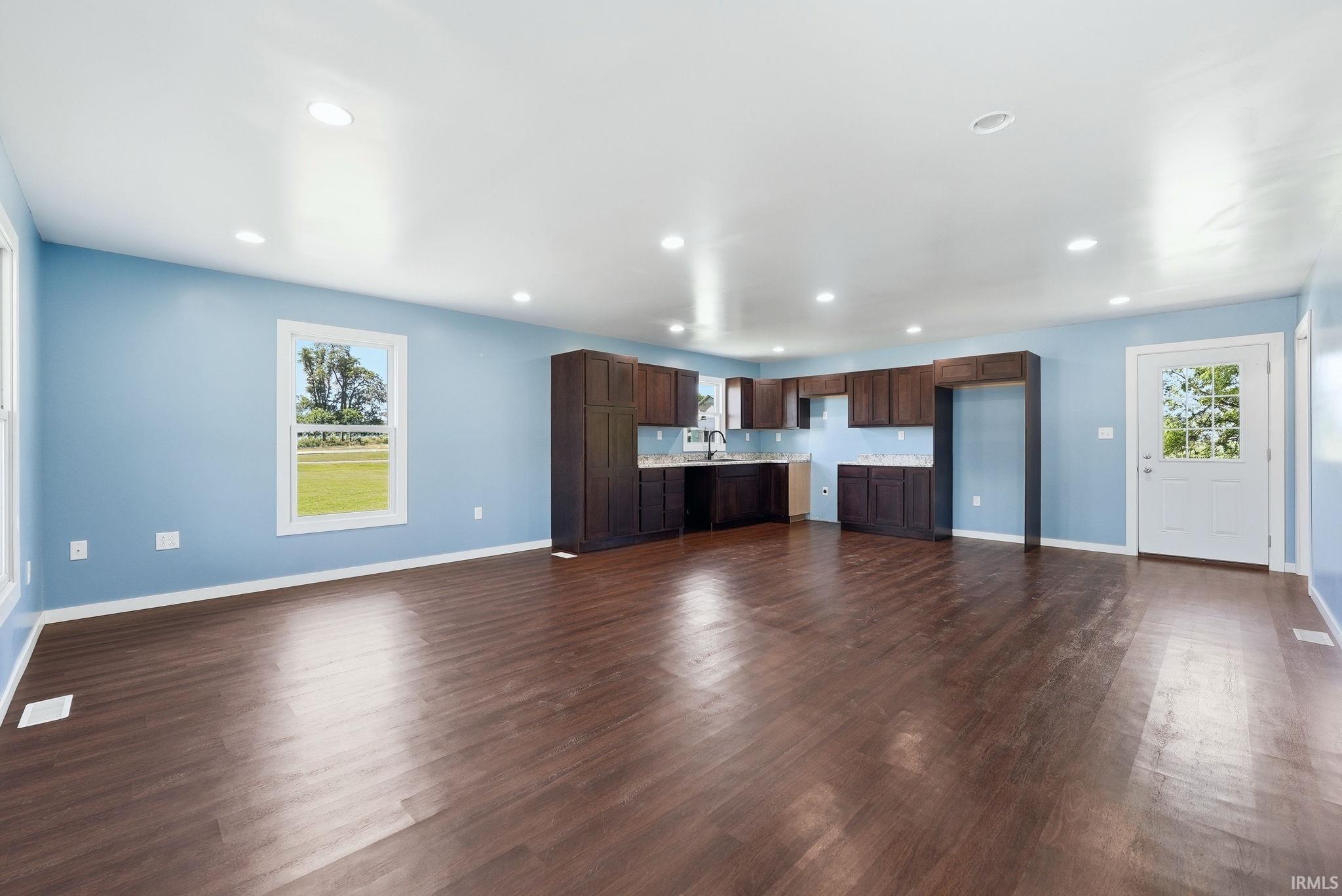 Expansive open-concept living area featuring wood-finish flooring, recessed lighting, and a modern kitchen