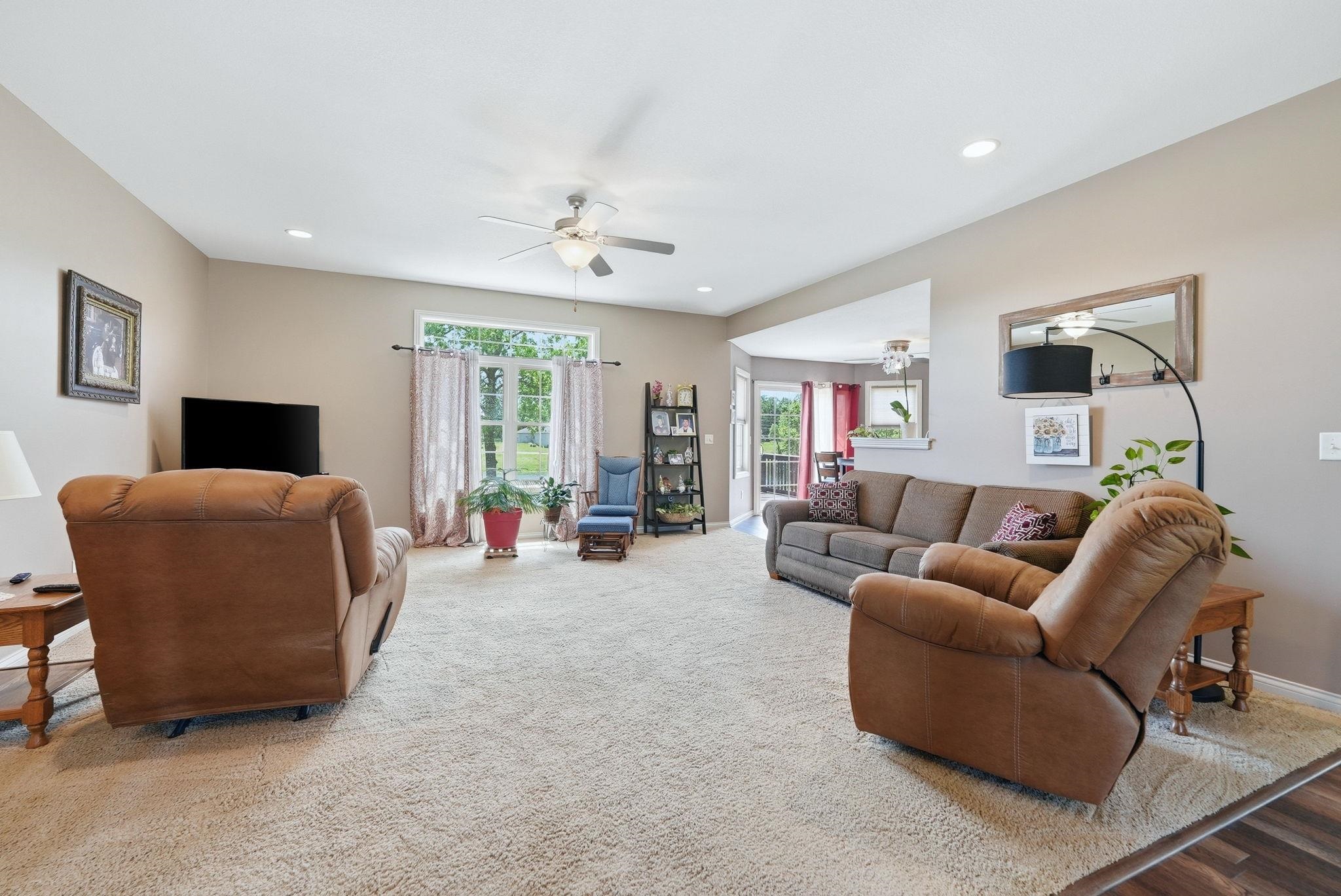 Spacious living area featuring neutral-toned walls, recessed lighting, and an overhead ceiling fan