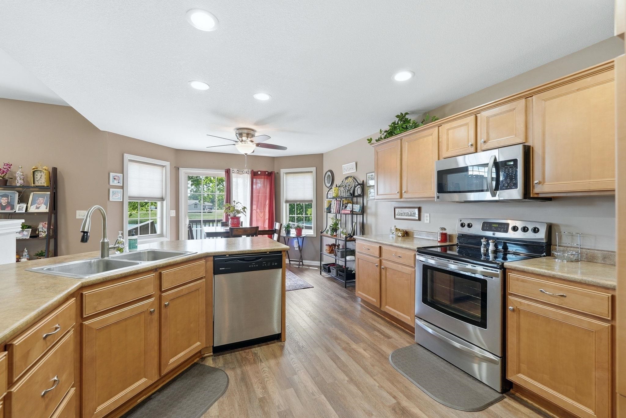 Kitchen featuring honey-toned cabinetry, stainless steel appliances, a double basin sink, recessed lighting, and wood-finish flooring
