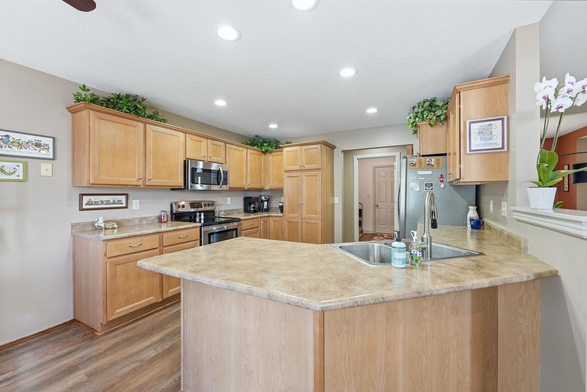 Kitchen featuring wood-finish cabinetry, stainless steel appliances, a double basin sink, recessed lighting, and wood-finish flooring