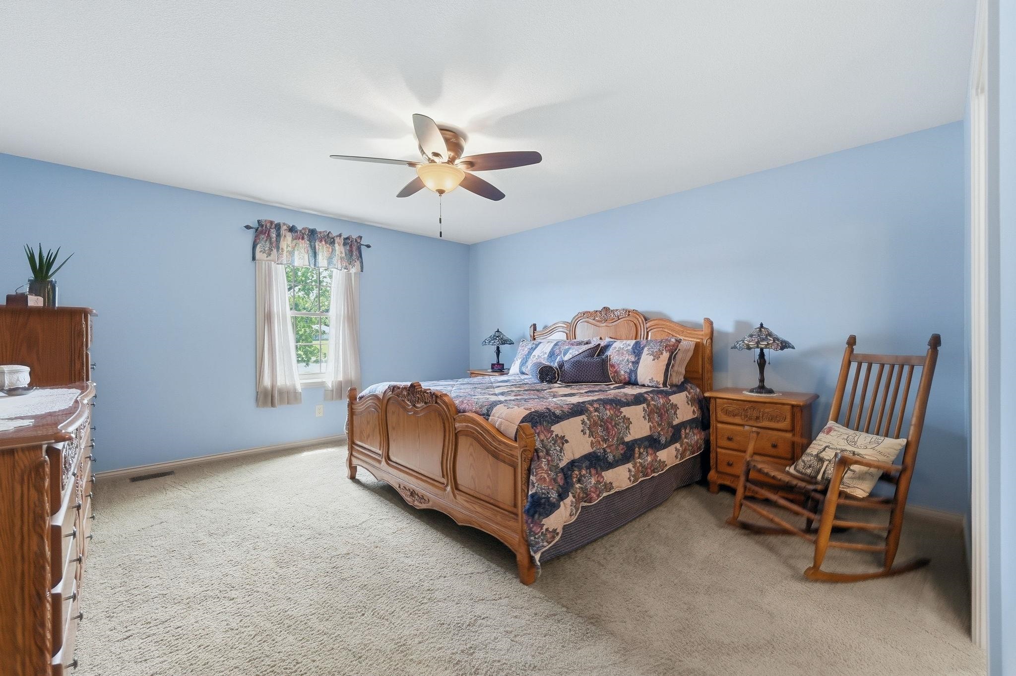 Carpeted room featuring a ceiling fan, a window with natural light, and light blue walls