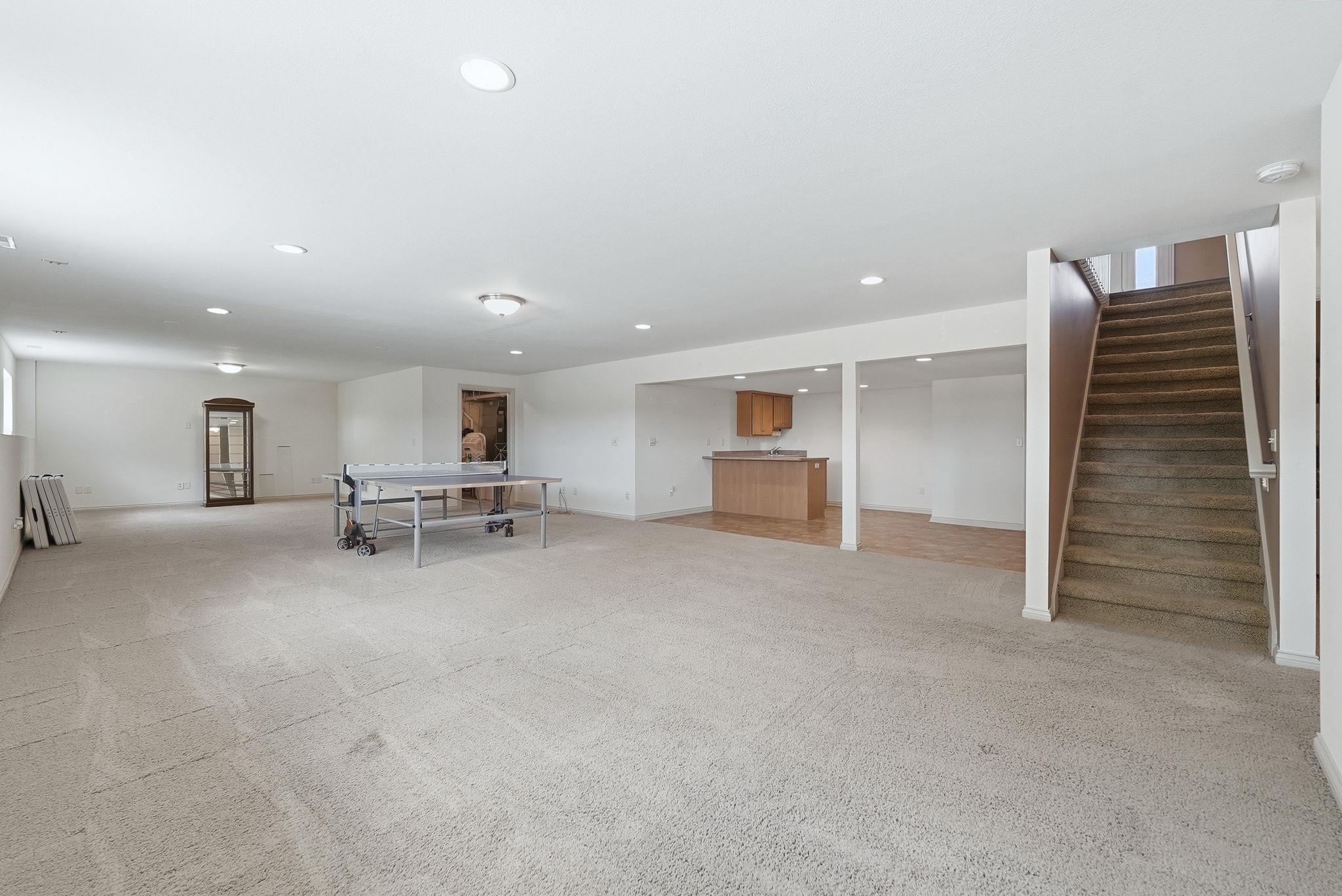 Expansive finished basement with recessed lighting and neutral carpeting