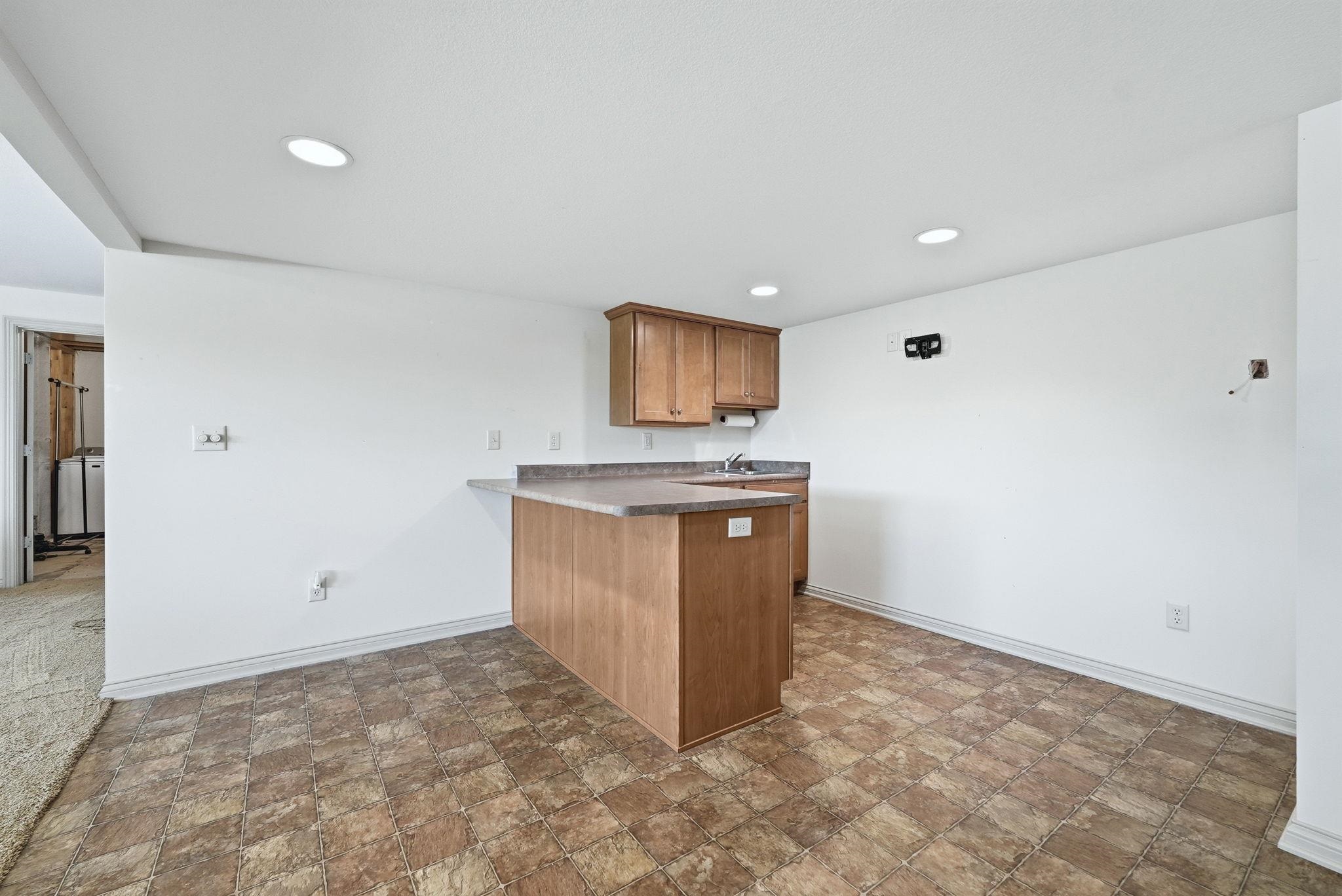 Compact kitchenette featuring wood-finish cabinetry, a sink, and an extended countertop