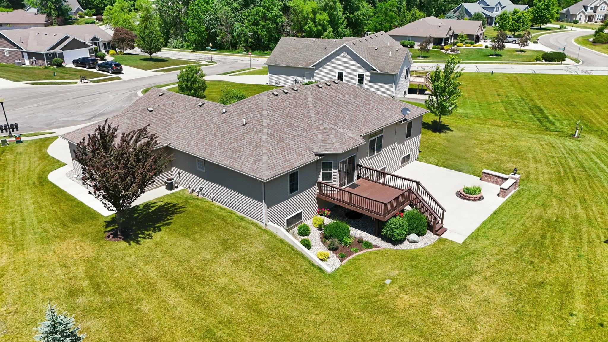 Expansive rear yard featuring a multi-level deck with stairs, a concrete patio, and a built-in stone fire pit