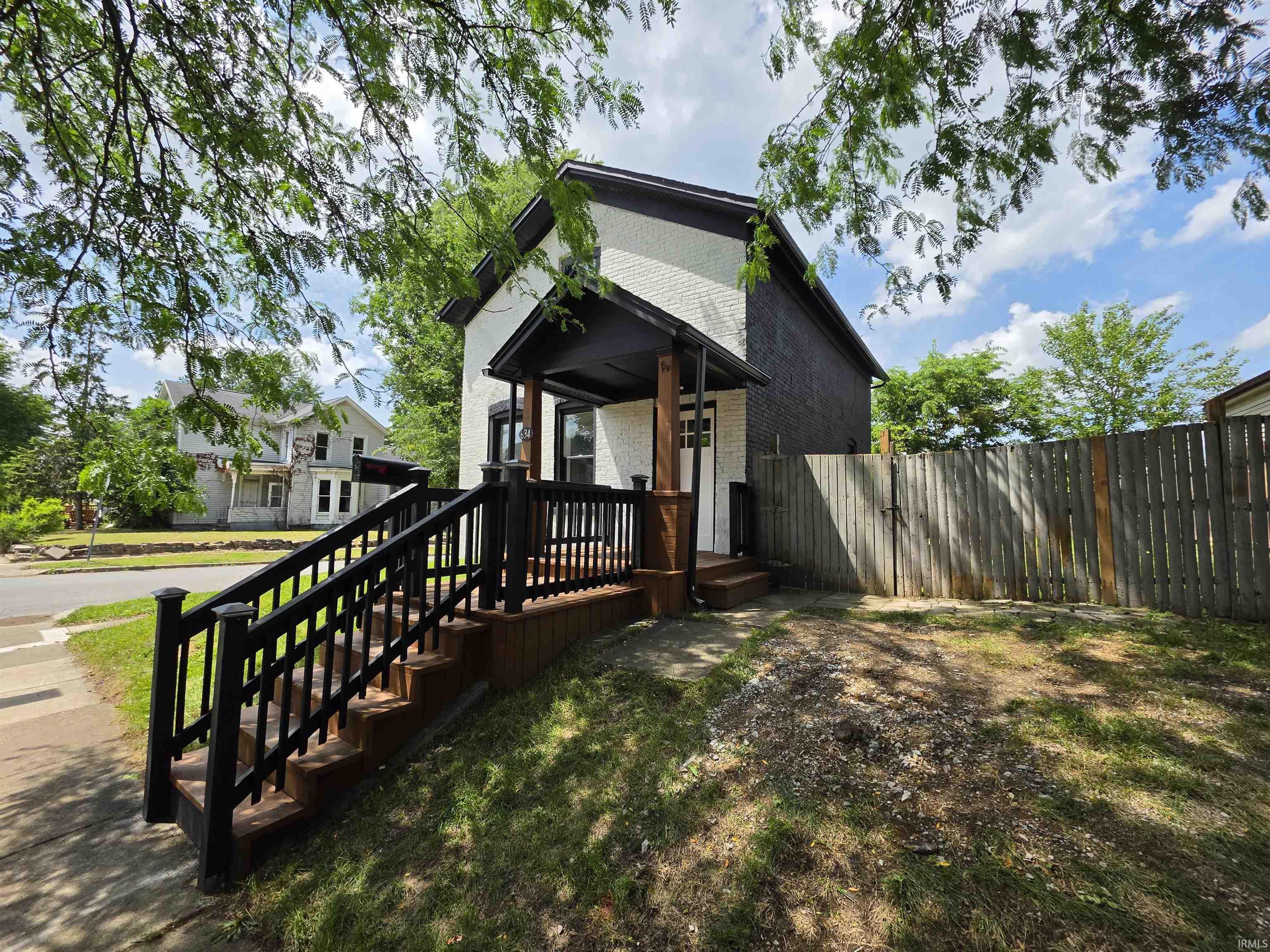 Two-story residence featuring white brick siding and a dark trim