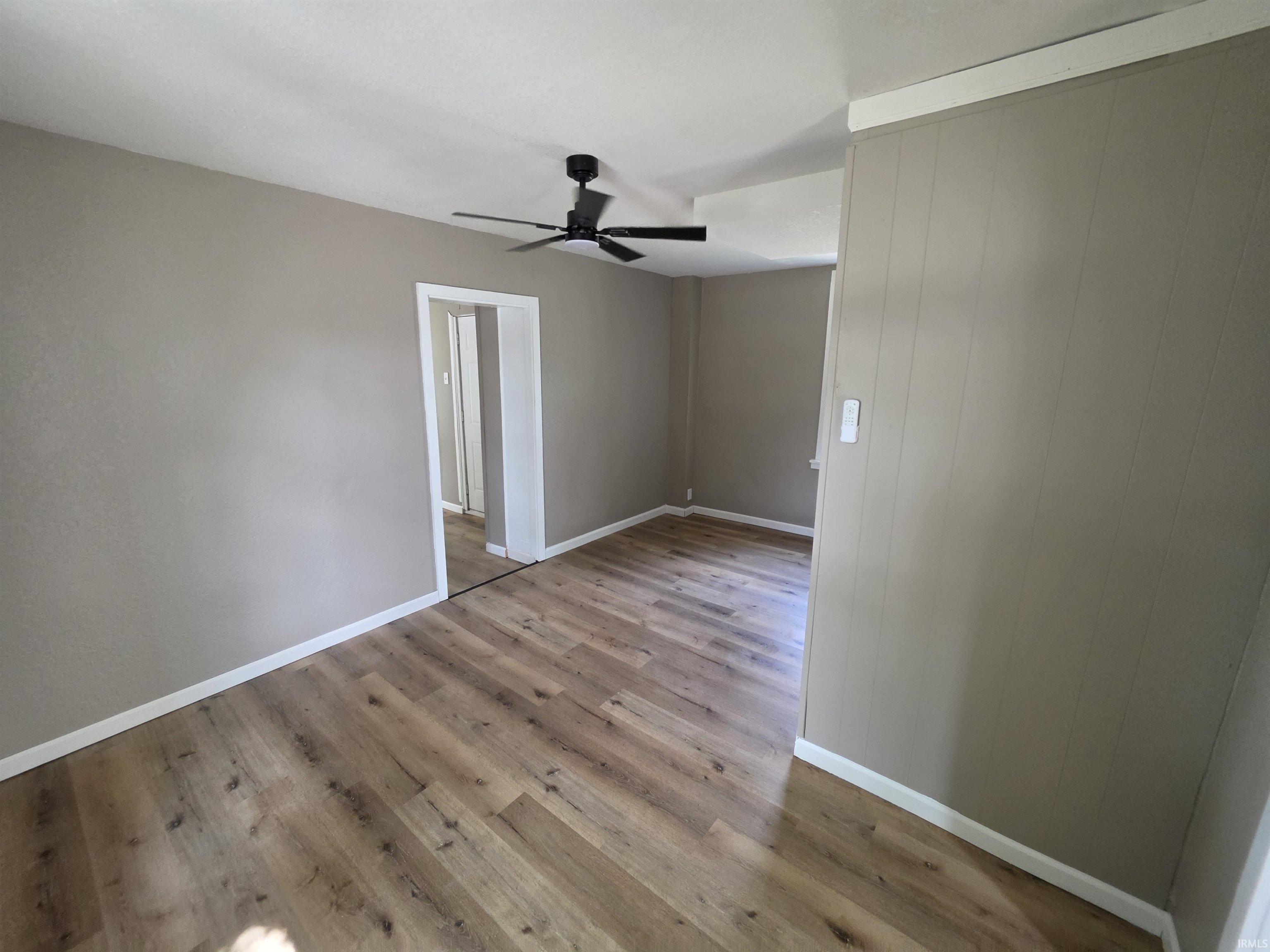 Spacious interior featuring wood-finish flooring, a contemporary ceiling fan, baseboard trim, and a neutral wall palette