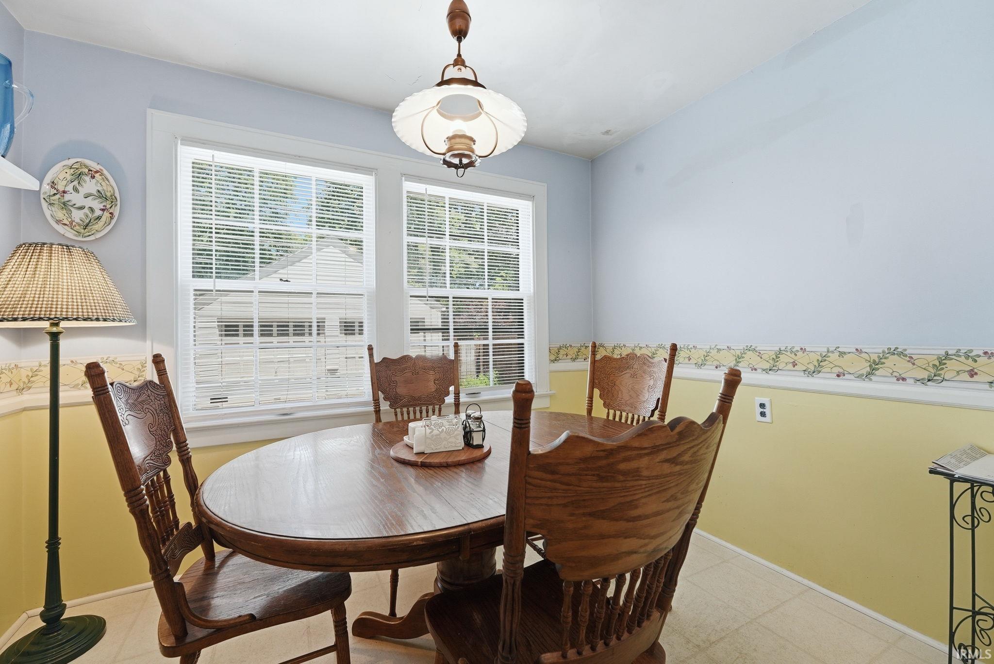 Dining area featuring a central chandelier, multiple windows with blinds, and light-toned flooring