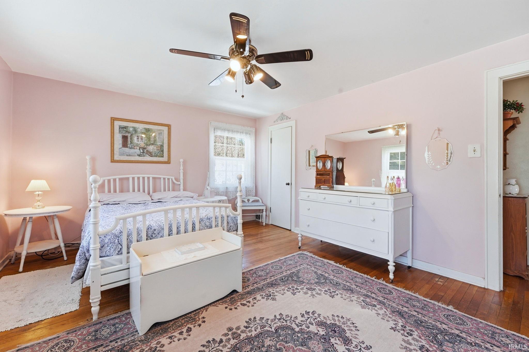 Interior room featuring wood-finish flooring, a ceiling fan with integrated lighting, and a window with white trim