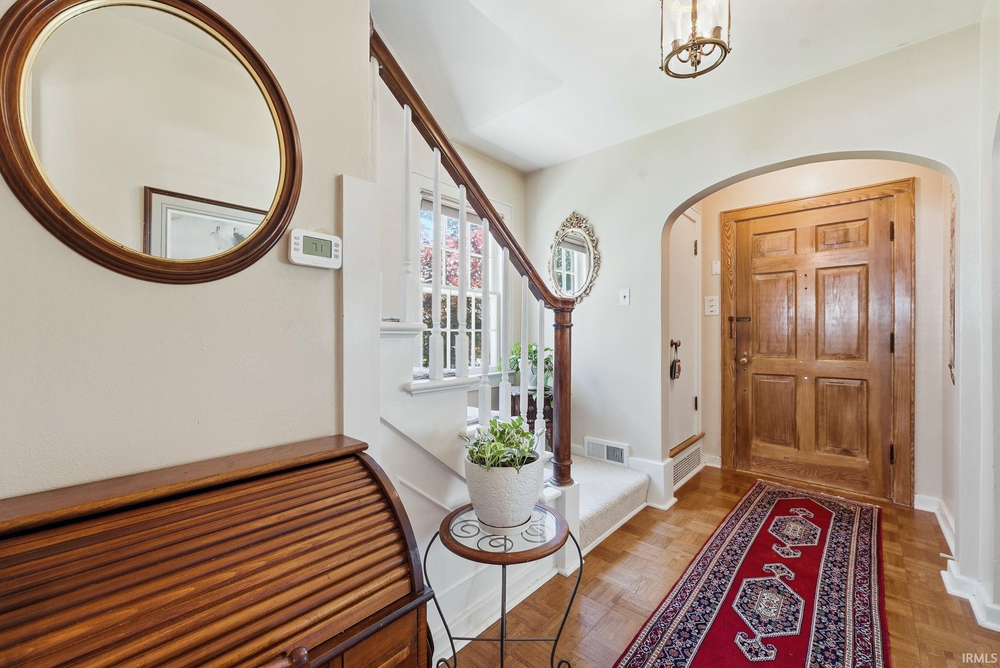 Entryway featuring a wood paneled door, arched doorway, and hardwood flooring