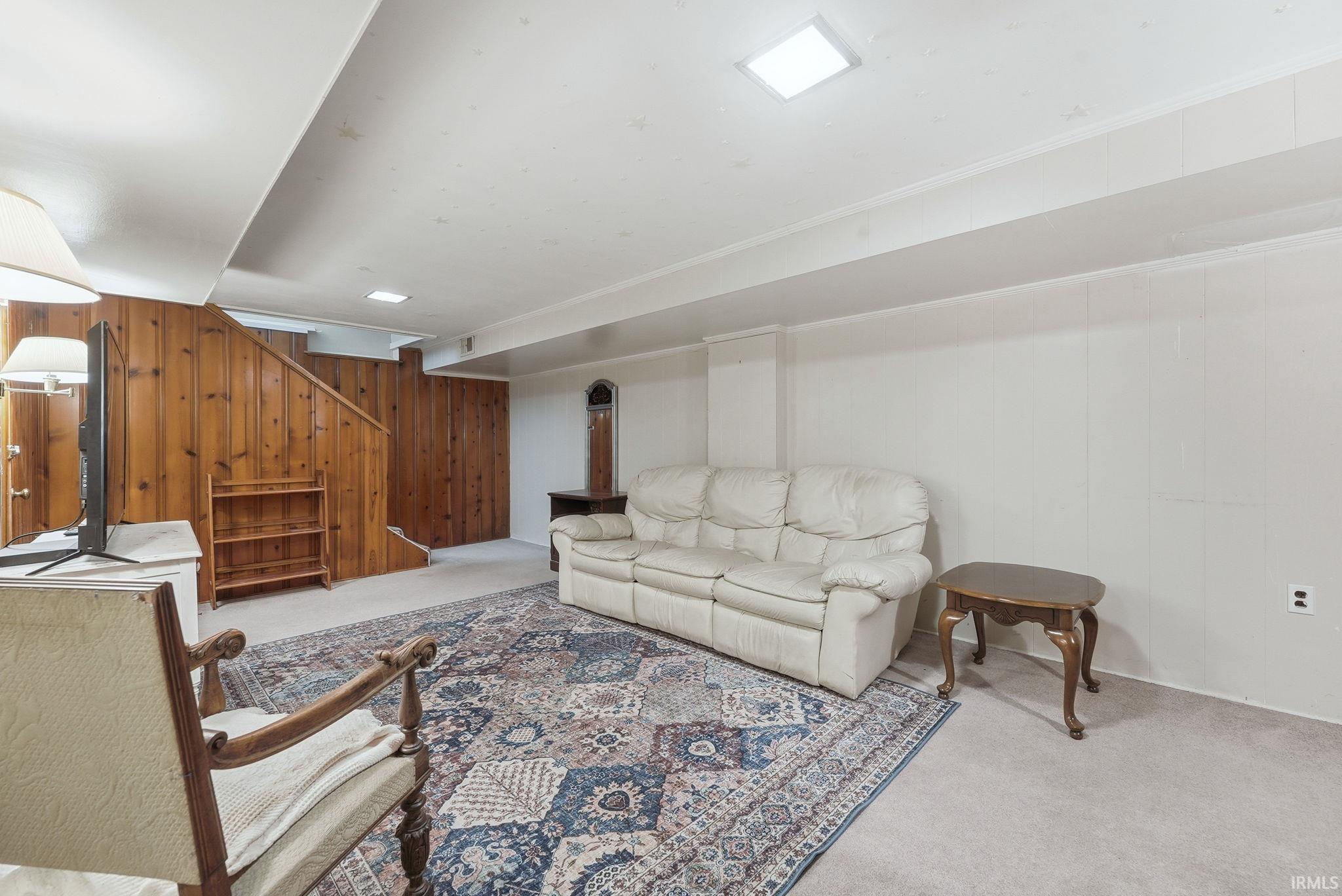 Interior space featuring wood paneling, carpet flooring, a drop ceiling with recessed lighting, and white wall paneling