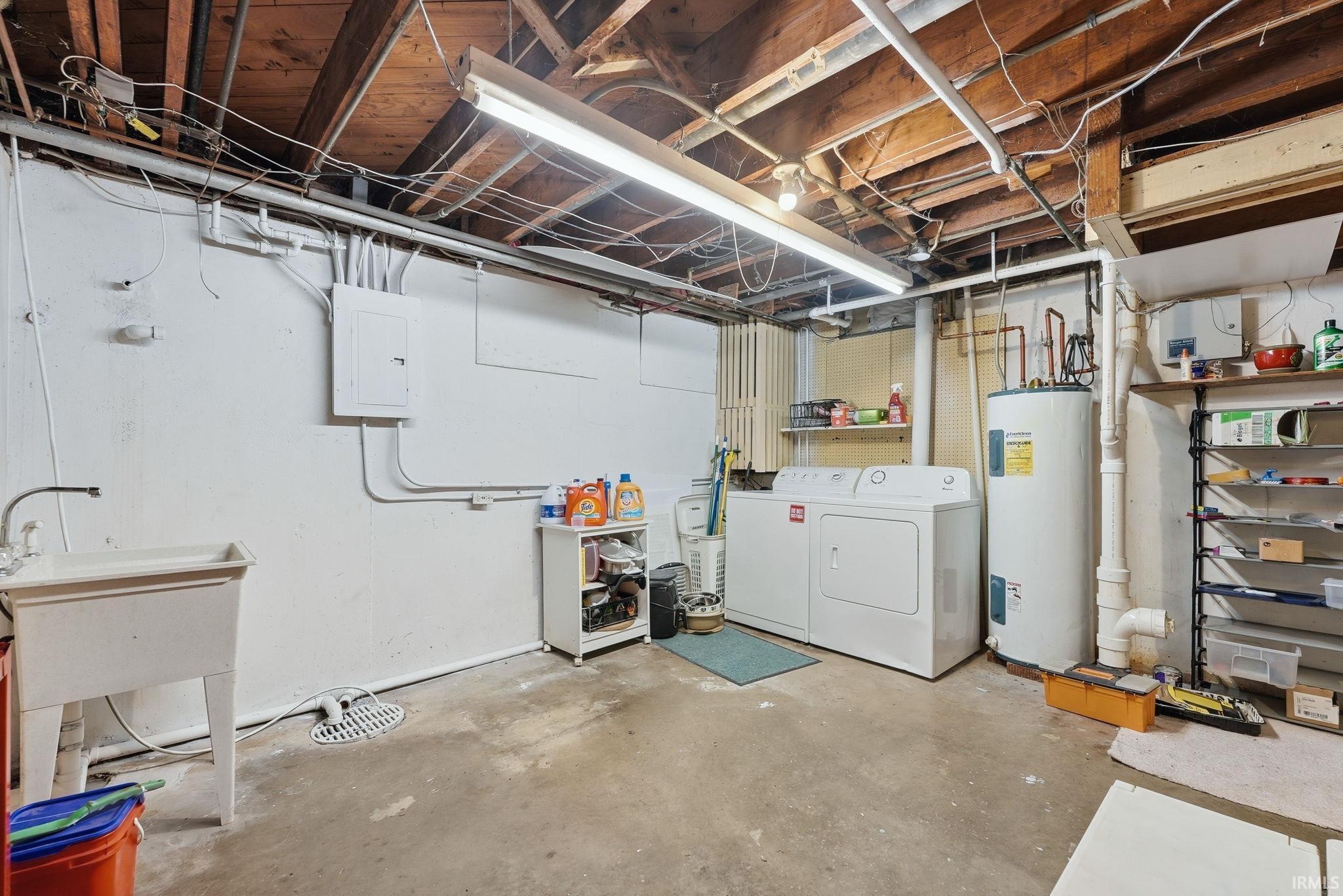 Utility area featuring a laundry sink, electric water heater, and exposed ceiling joists
