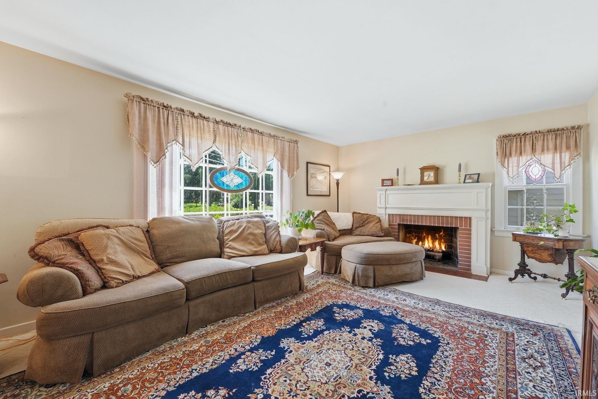 Living area featuring a brick fireplace with a white mantel, large windows, and neutral wall tones