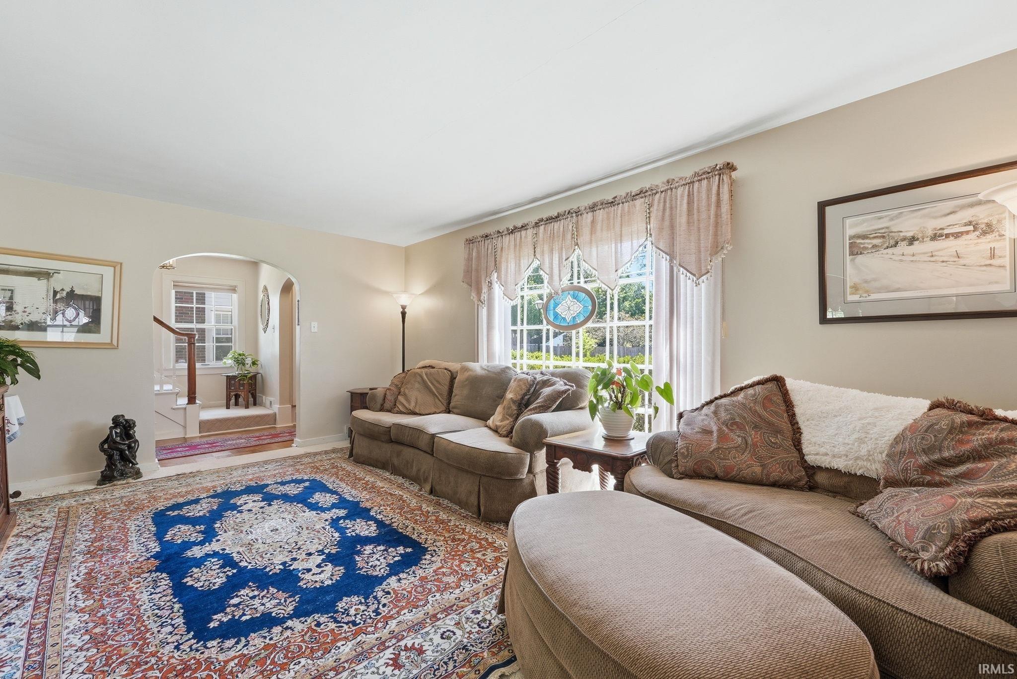 Living area with light beige wall paint, wood-finish flooring, and a large window