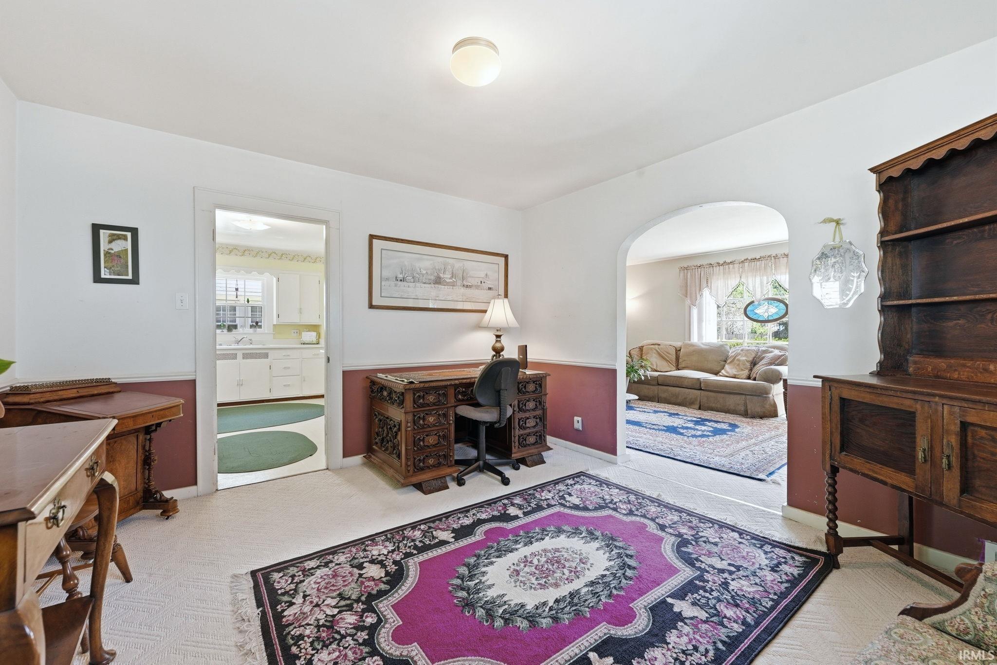 Versatile interior space featuring light-toned carpeting and a two-tone wall treatment with a white upper and red-toned lower half